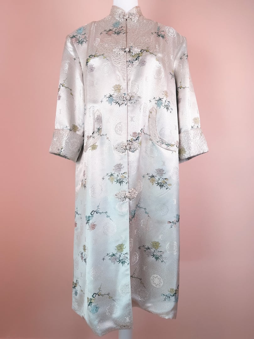 A silver 1970s women's Harmony Silk Cheongsam coat featuring floral patterns and three-quarter sleeves.