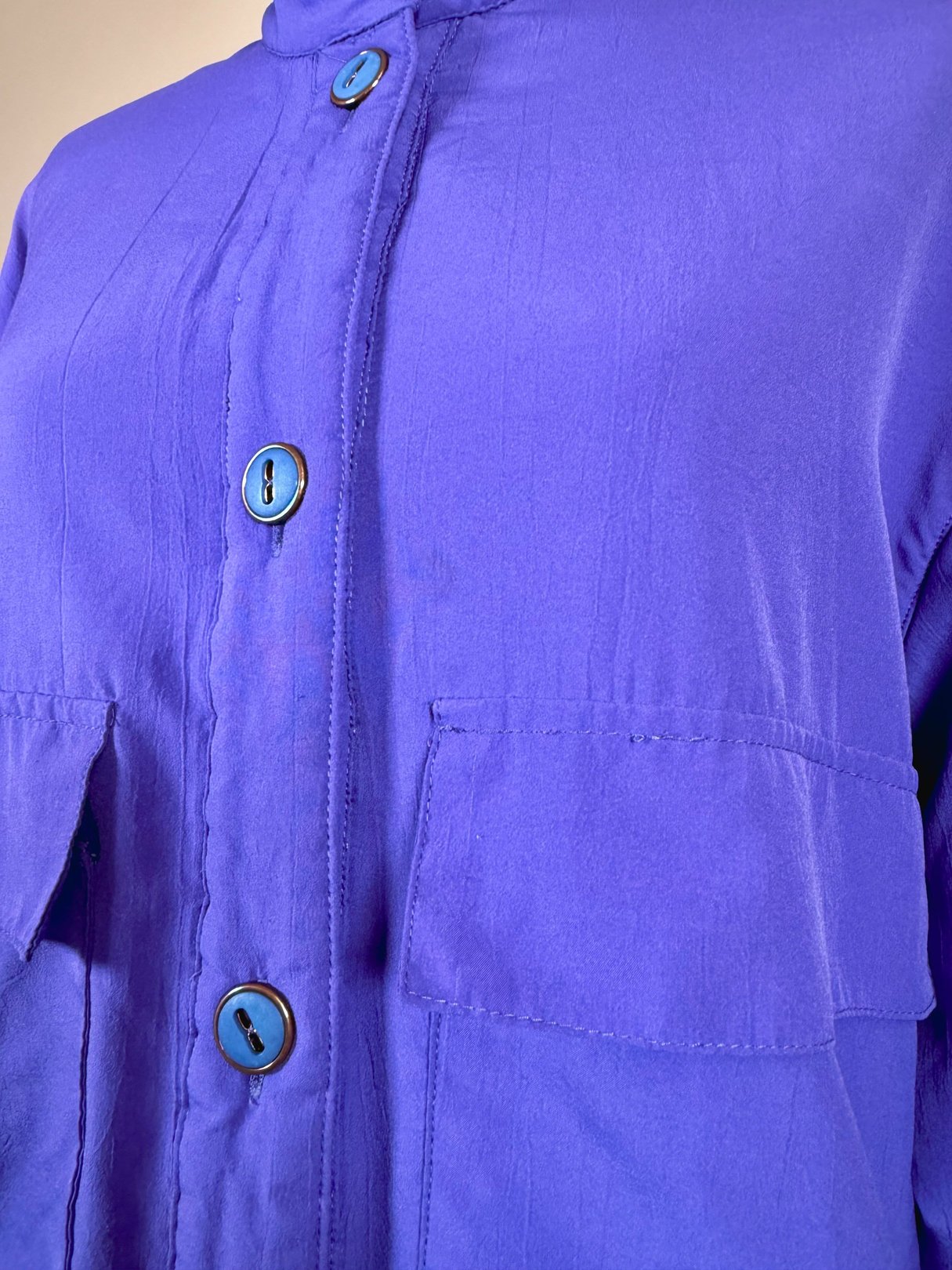 Vibrant violet women's jacket from the 1980s featuring blue buttons and two front pockets.