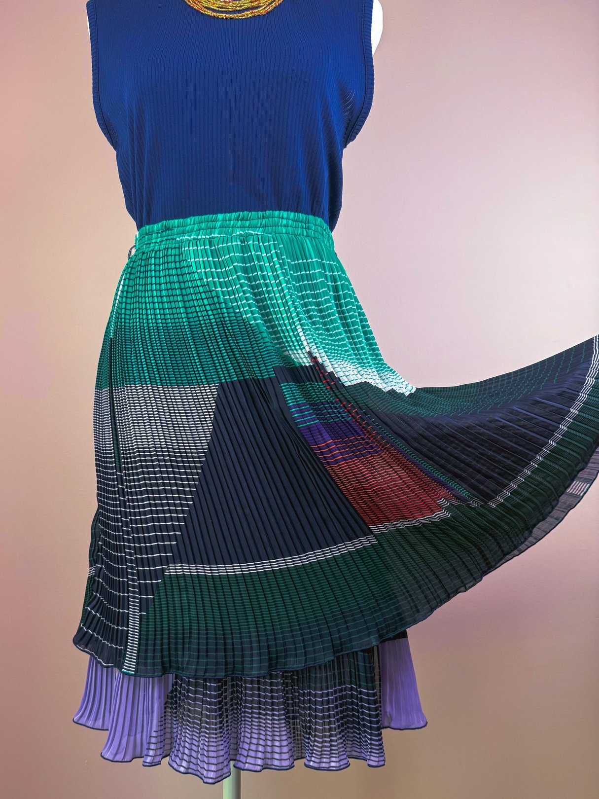 Pleated green skirt featuring a mix of patterns and colors, styled for women in a 1970s aesthetic.