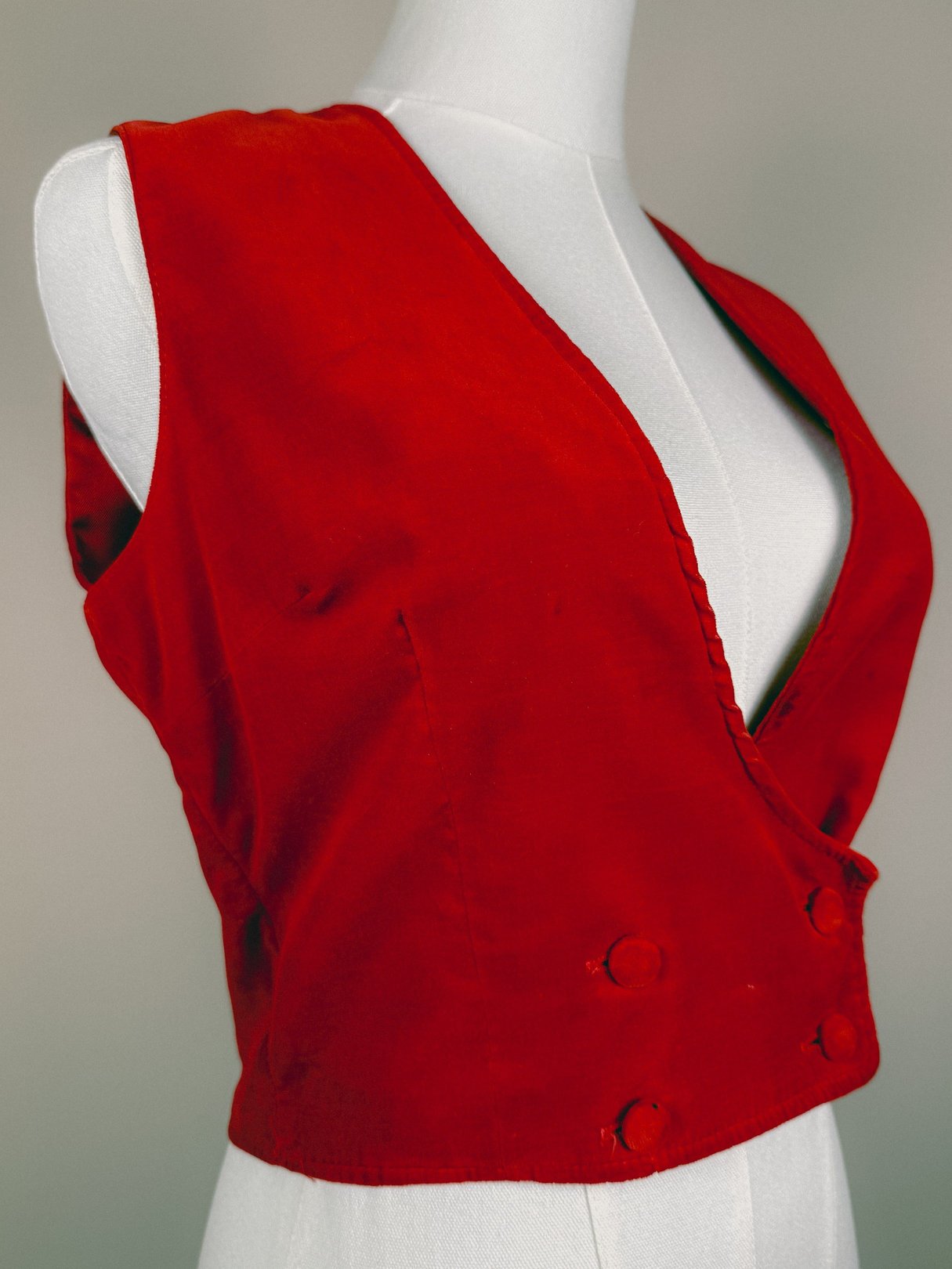Red velvet women's vest from the 1970s featuring a deep V-neck and double-breasted button closure.