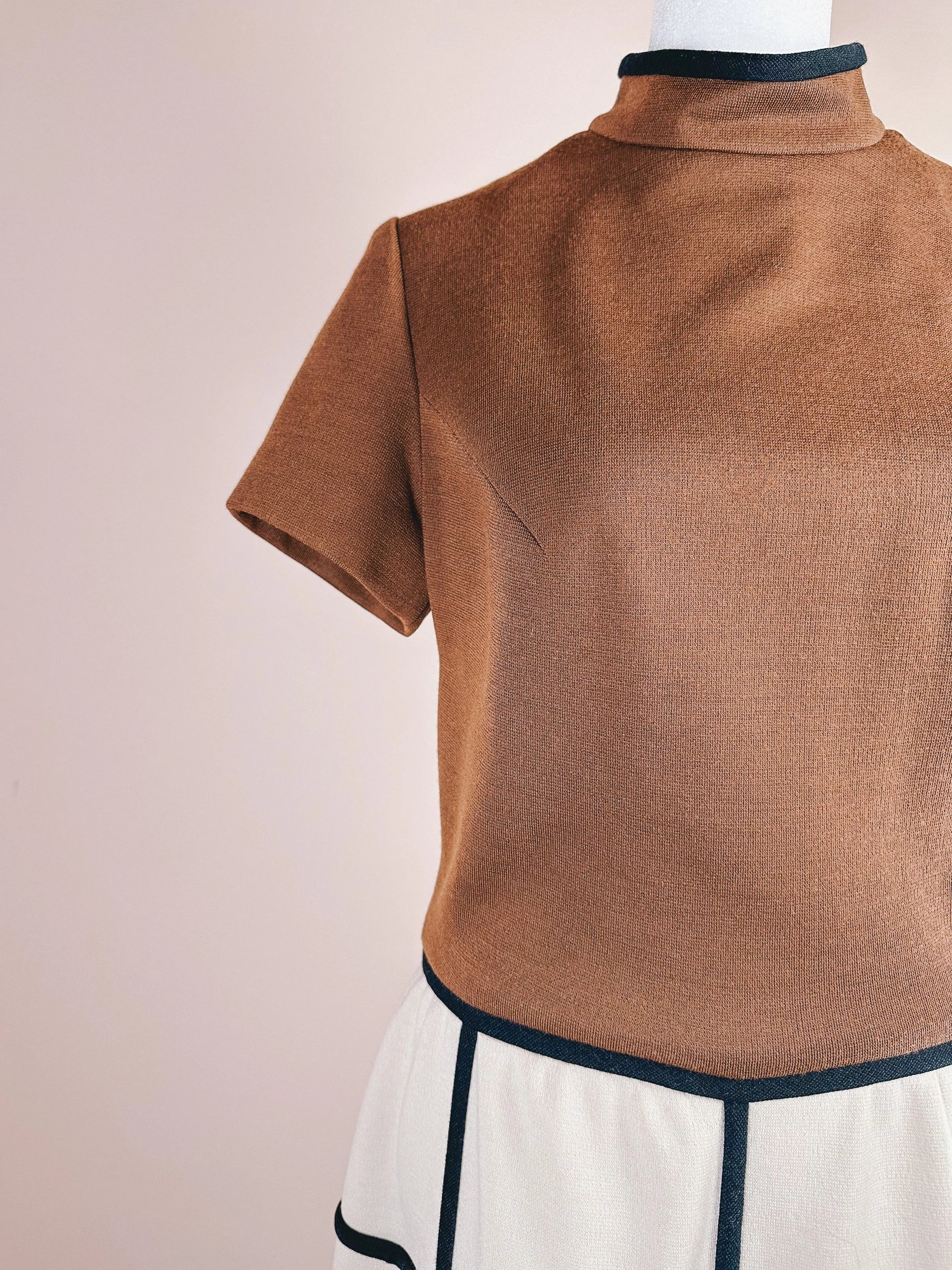Short-sleeve brown top paired with white trousers featuring black trim.
