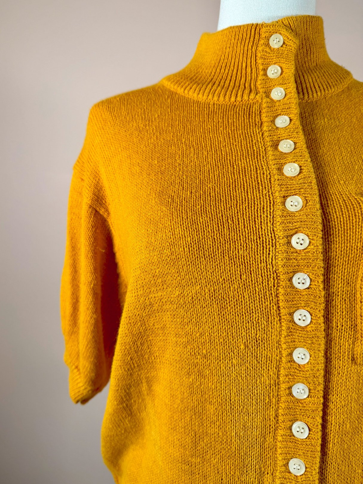 Persimmon orange 1980s women's sweater featuring a high neck and a row of cream buttons down the back.