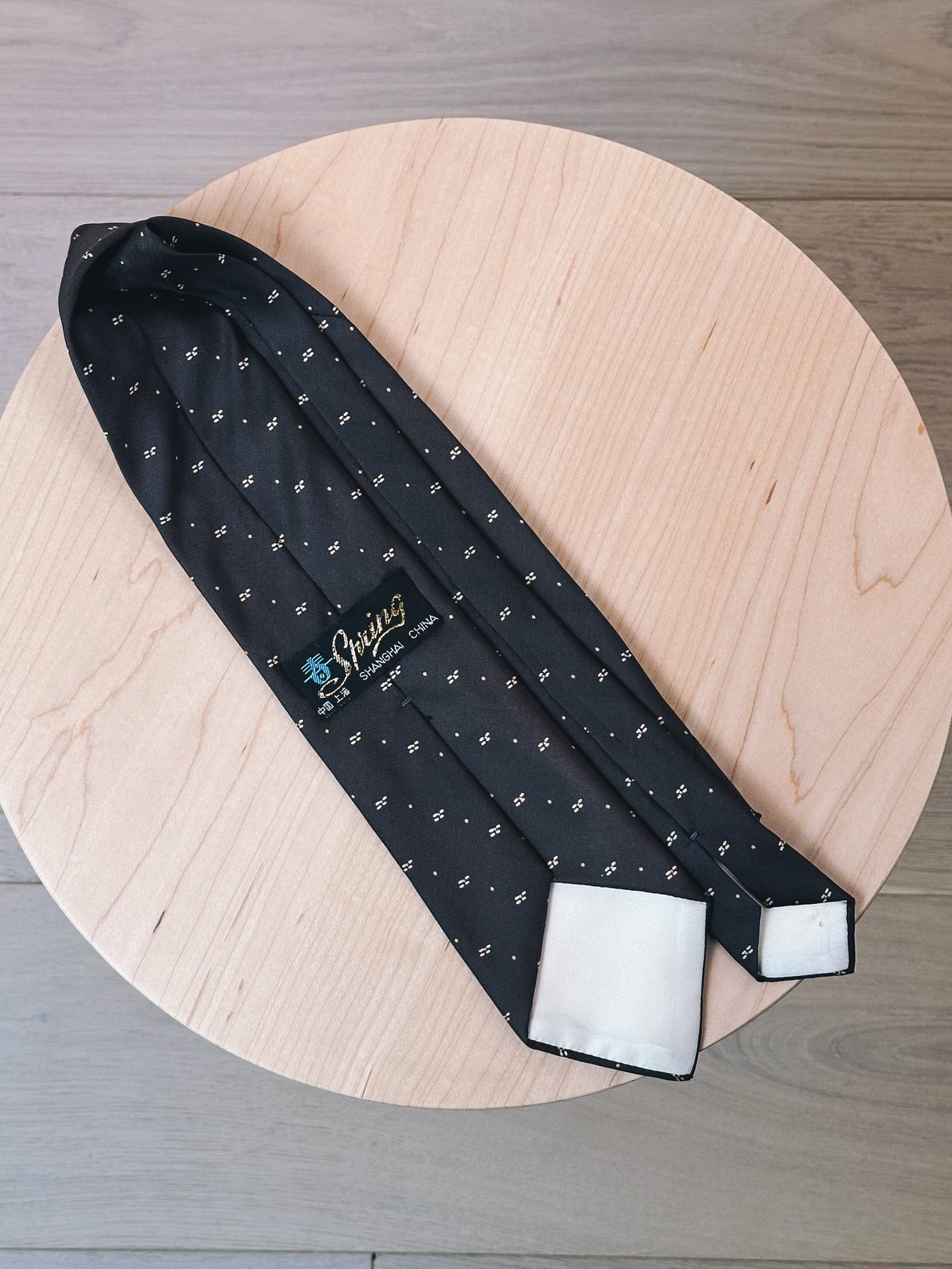 Brown tie with yellow dot pattern from the 1970s, designed for women, displayed on a round wooden surface.
