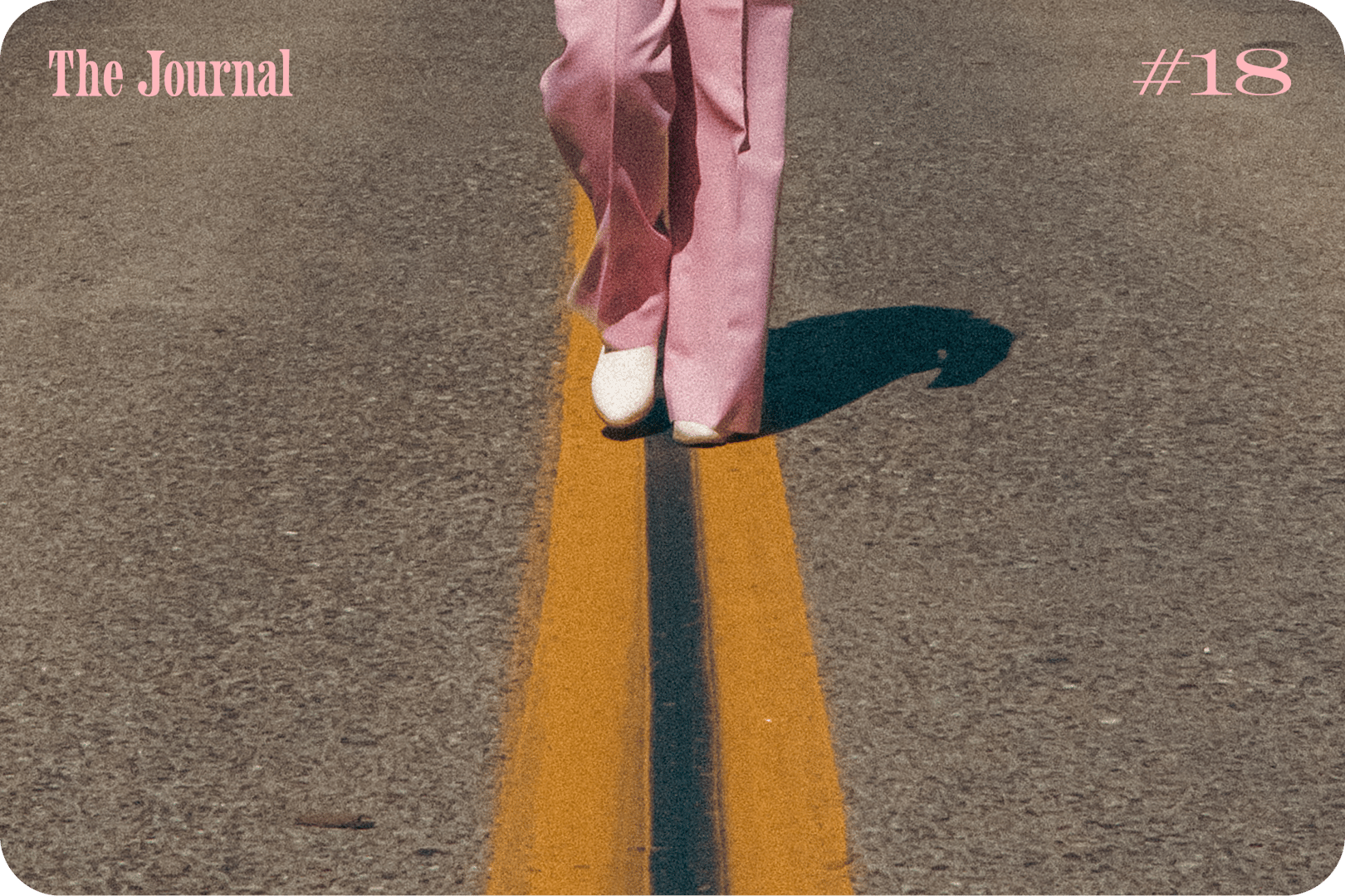 A person wearing pink wide-leg pants and white shoes walks along a yellow line on a road.