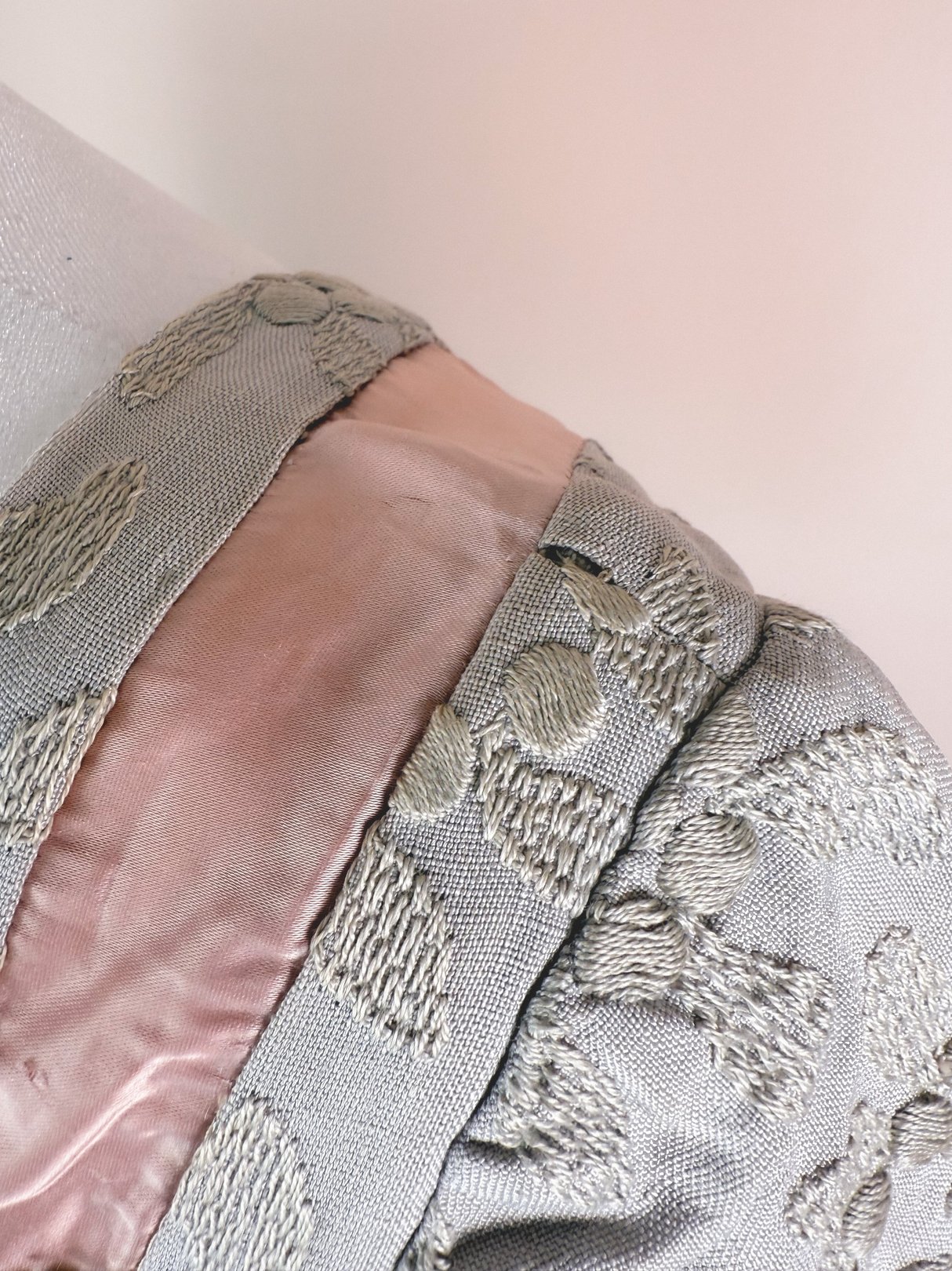 A 1950s women's dress in slate blue featuring satin detailing and embroidered patterns on the fabric.