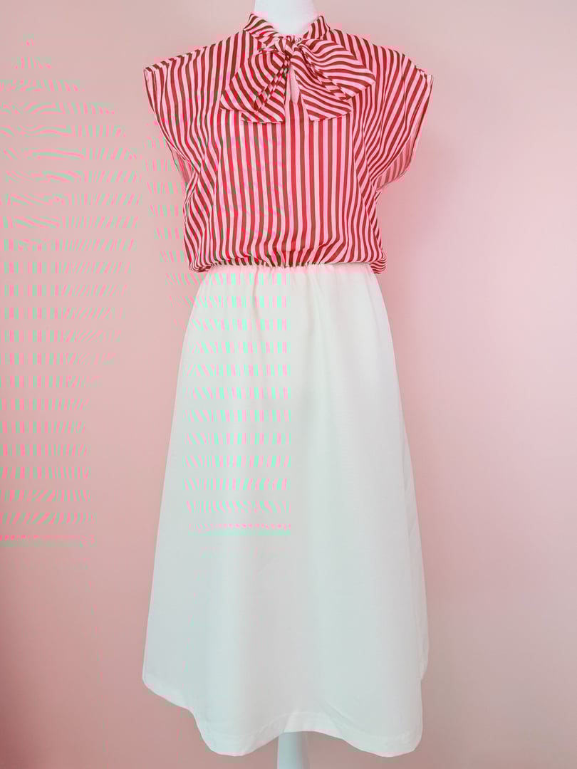 Red and white candy stripe dress with a bow tie at the neckline, featuring a fitted top and a flowing white skirt, styled for women in the 1970s.