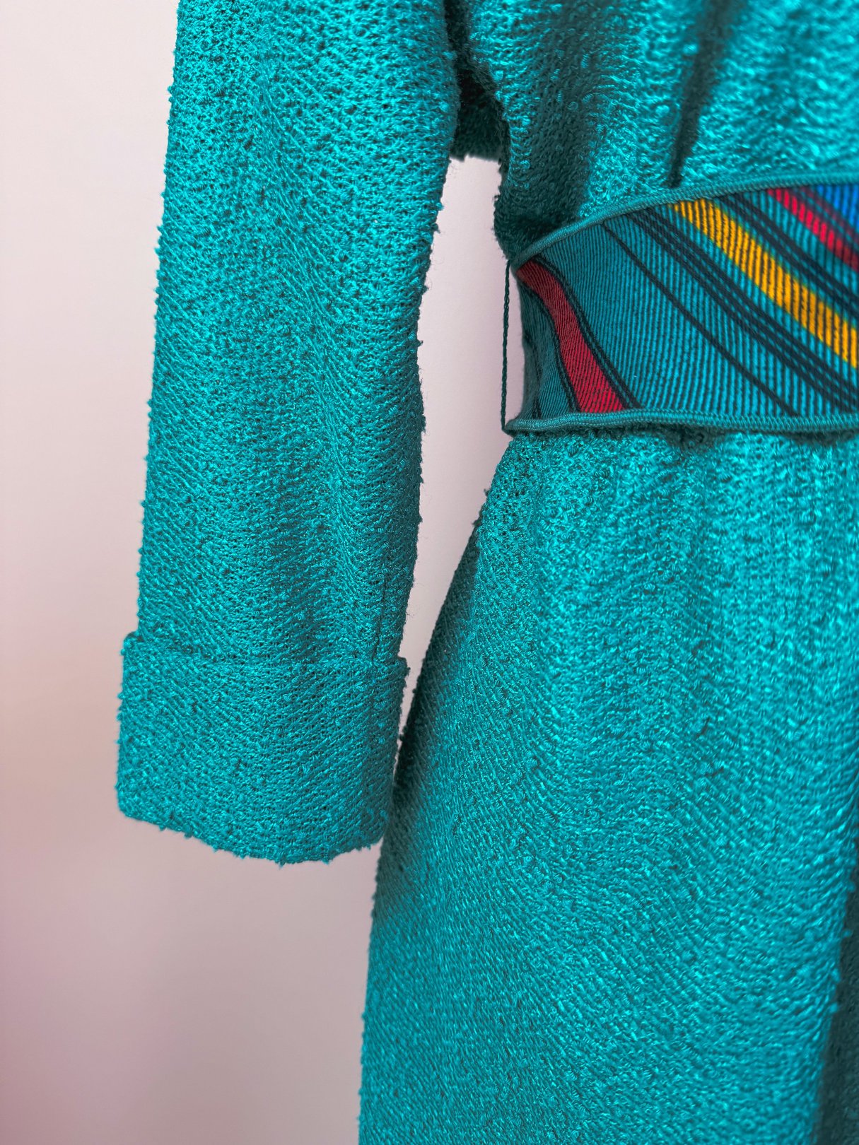 Teal Tempo Dress featuring a textured fabric with a colorful striped belt, tailored for women and inspired by 1980s fashion.