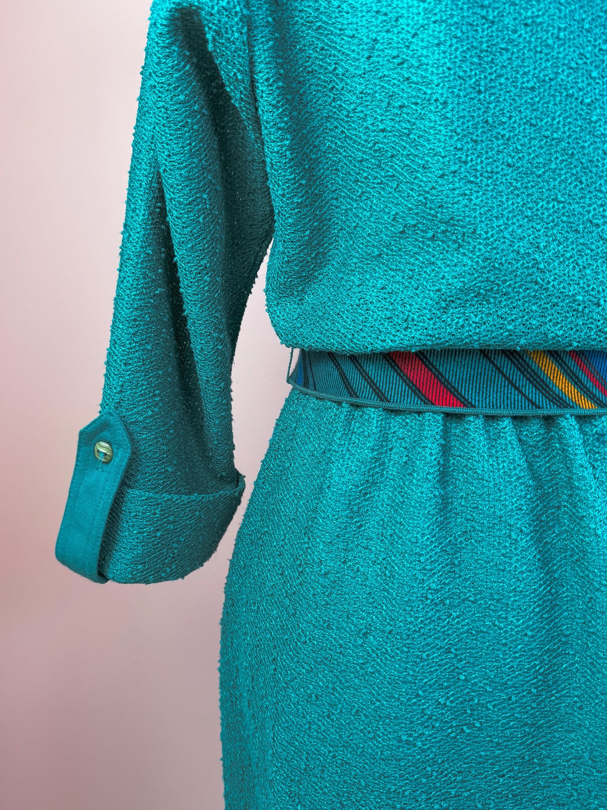 Teal 1980s dress for women featuring a textured fabric and a colorful striped belt.