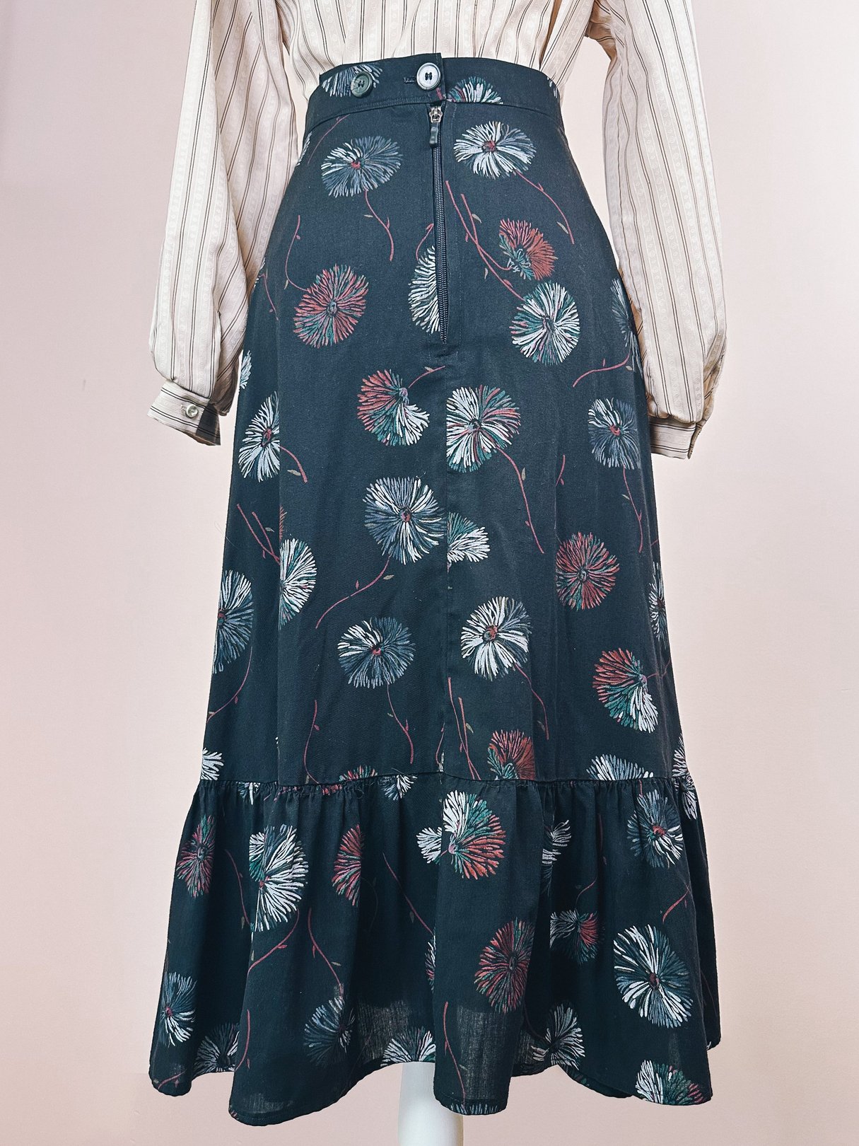 Black 1970s women's dandelion ruffle skirt featuring a floral pattern and a button closure at the waist.