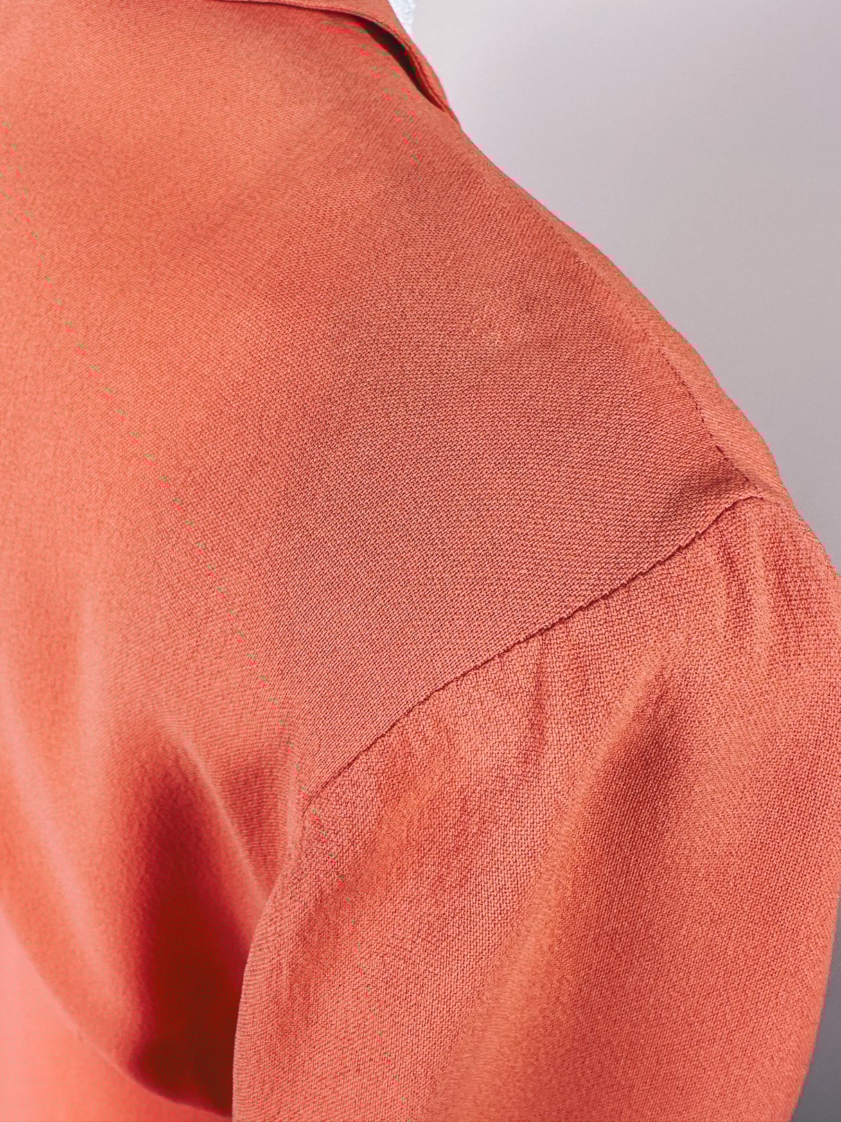 Coral 1940s-style dress featuring a fitted shoulder and a smooth texture.