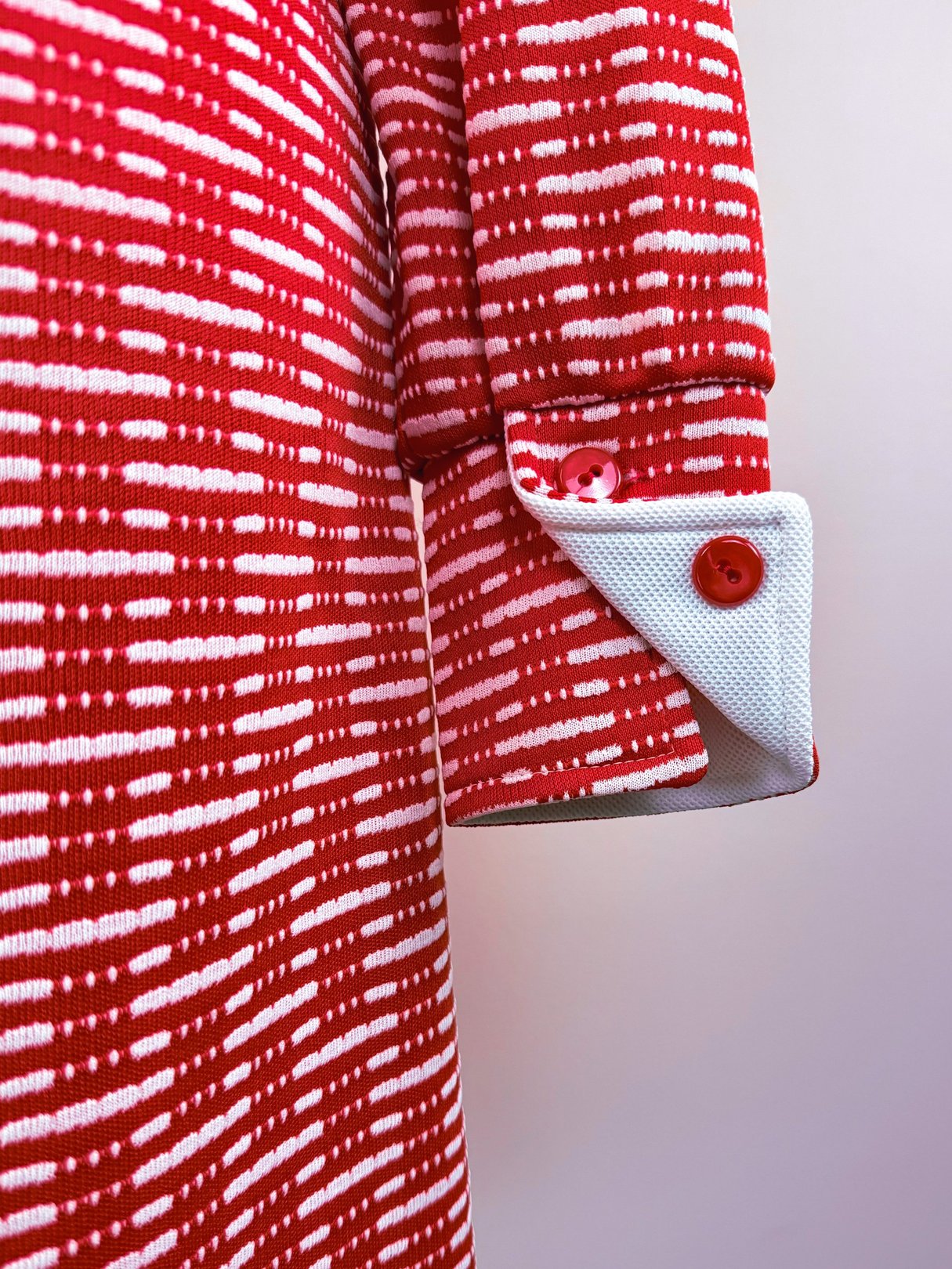 Red knit dress featuring a textured pattern and white accents on the cuffs, designed for women in the 1970s.