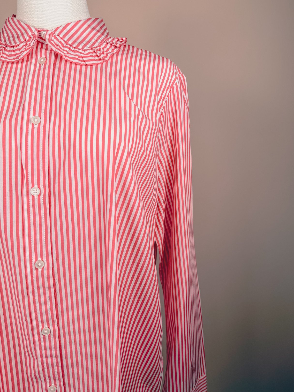 Red and white striped button-down top with a ruffle collar, featuring long sleeves and a relaxed fit, embodying a 1970s style.