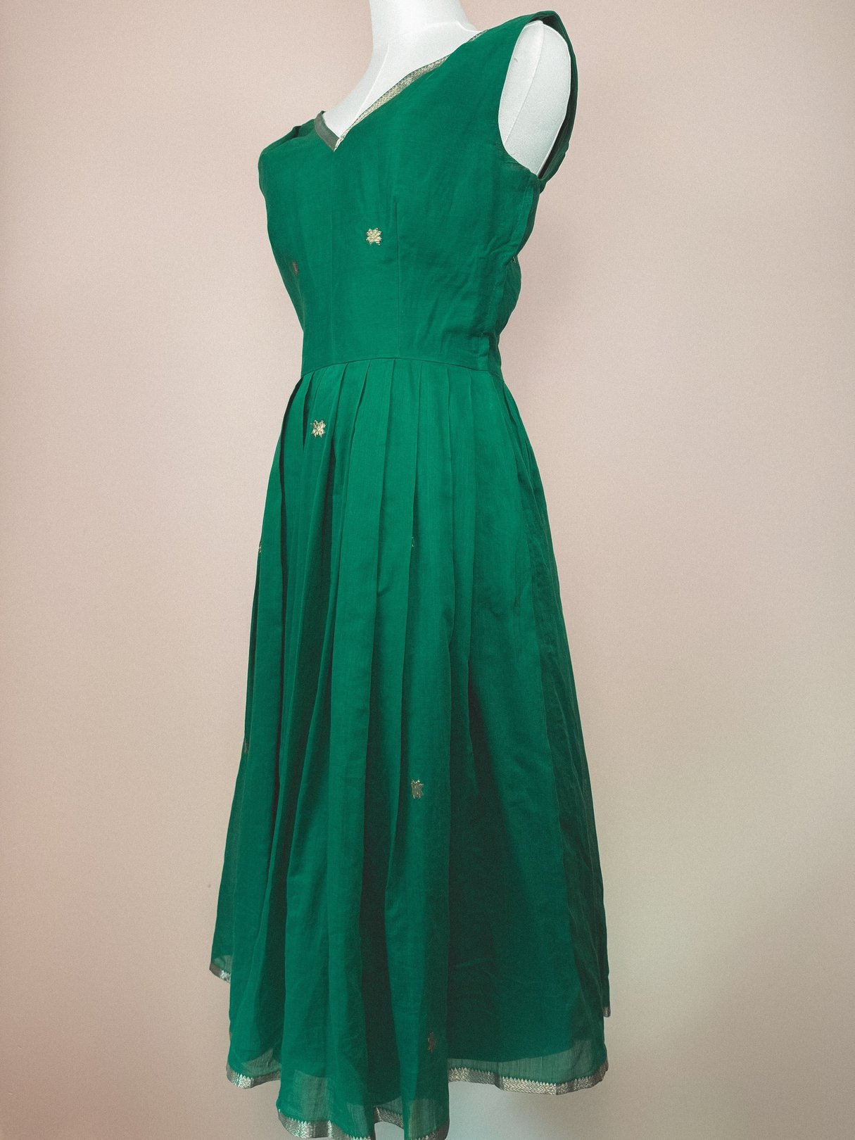 A green, 1950s-style women's dress featuring a starburst design and a fitted bodice with a flared skirt.