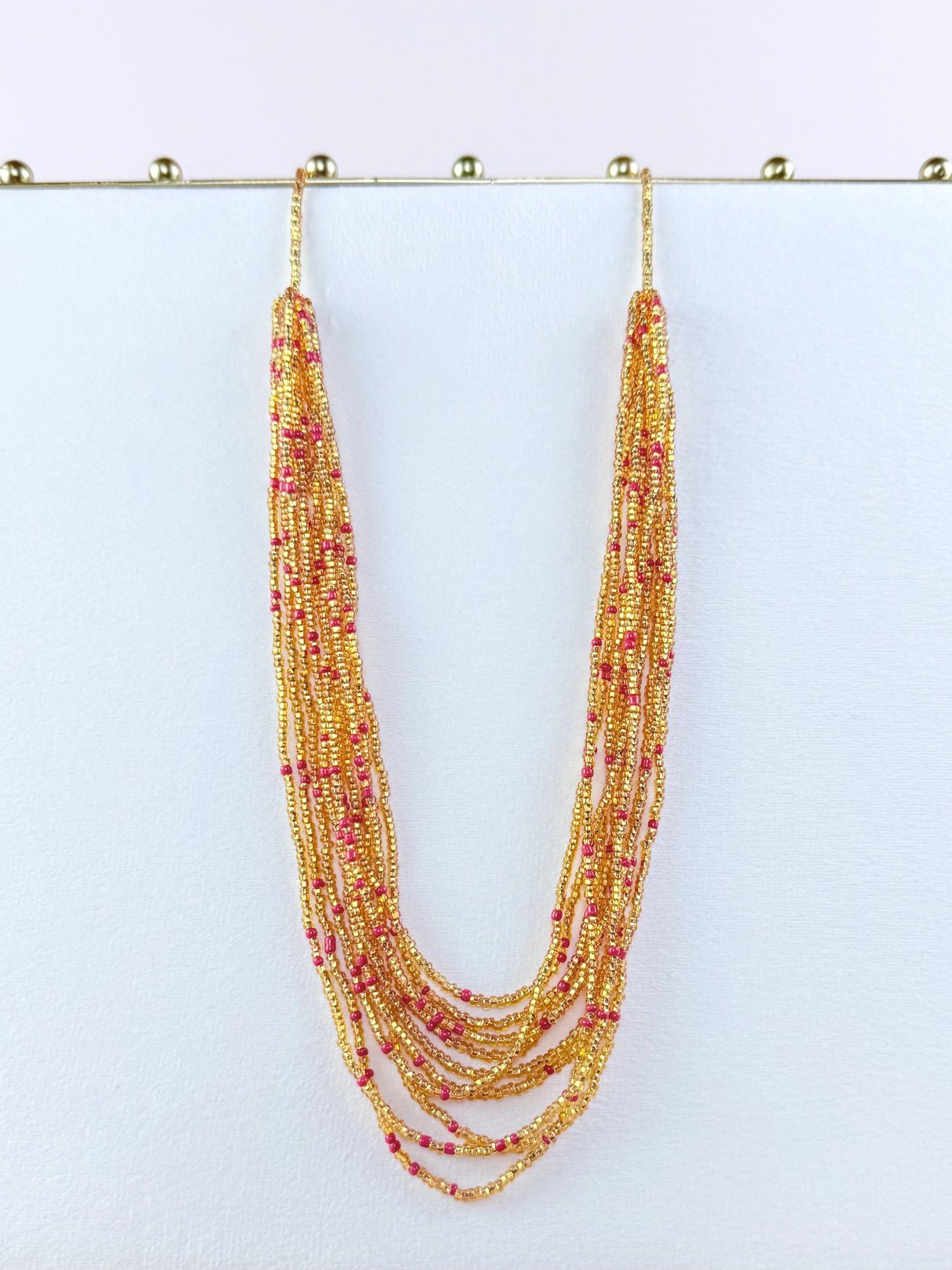 Colorful multi-strand necklace featuring gold and pink beads.