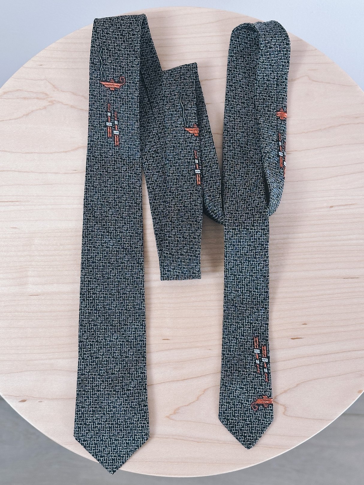 Black skinny tie featuring a 1950s design with colorful embroidered elements.