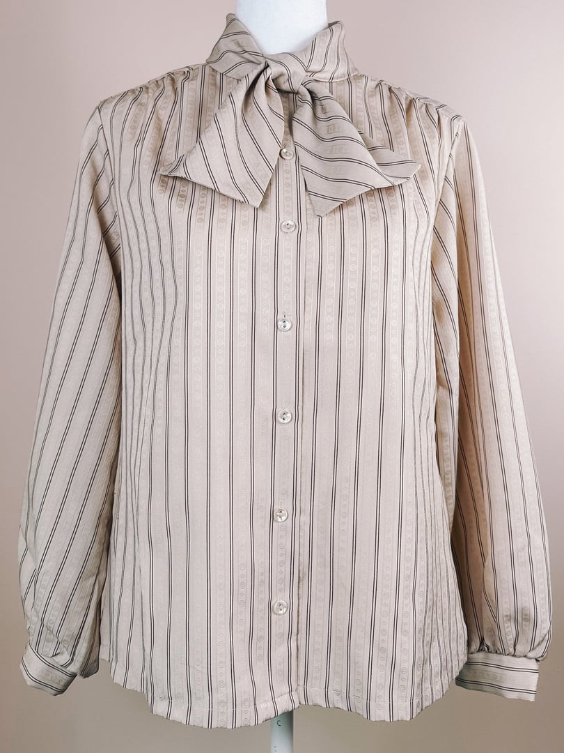 Maroon striped blouse with a bow tie neckline, featuring button closures and long sleeves.