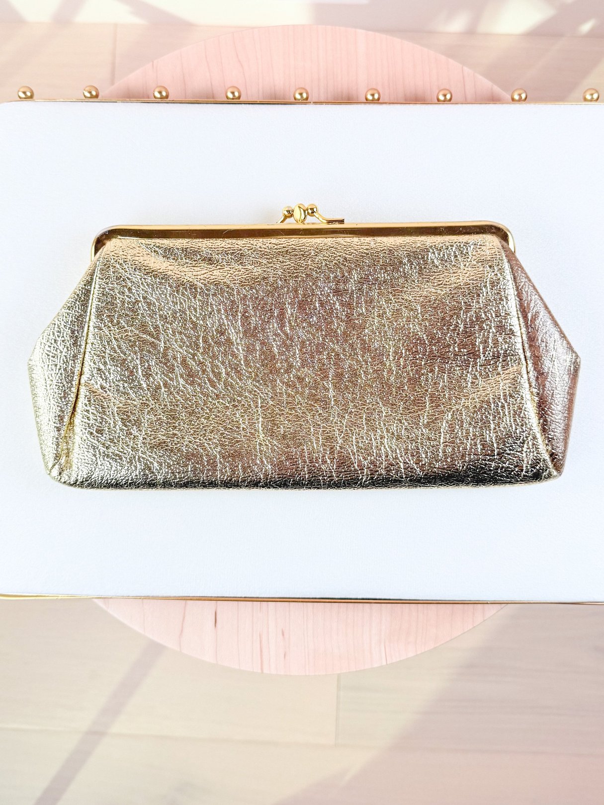 A 1950s women's clutch bag in gold with a textured surface and a metallic finish.