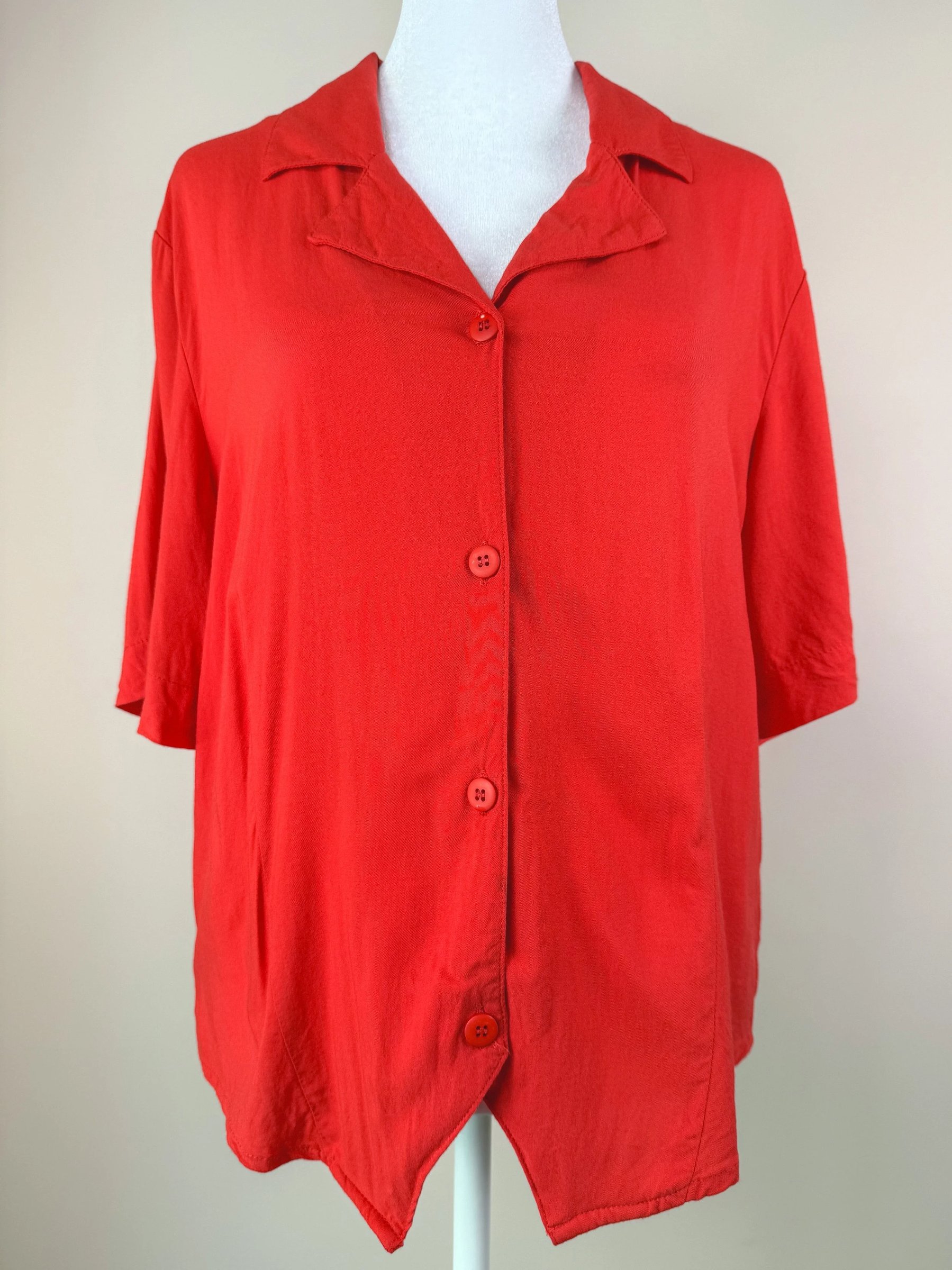 Red short-sleeve button-up shirt displayed on a mannequin against a neutral background.