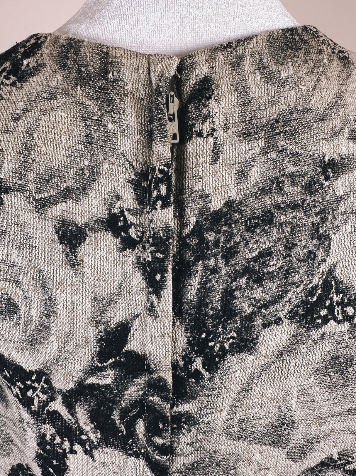 Back view of a 1950s women's dress featuring a black and cream rose pattern and a zipper closure.