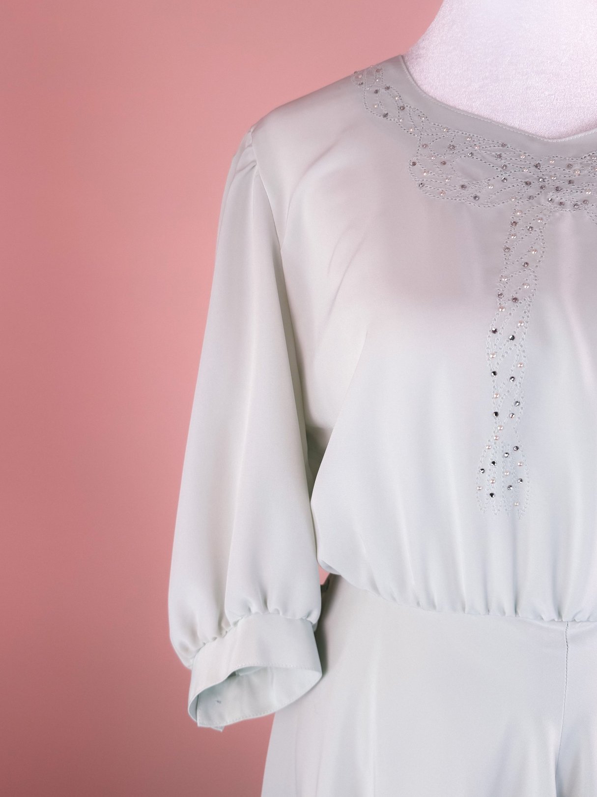 Mint green 1980s dress with sparkly embellishments along the front and voluminous sleeves.