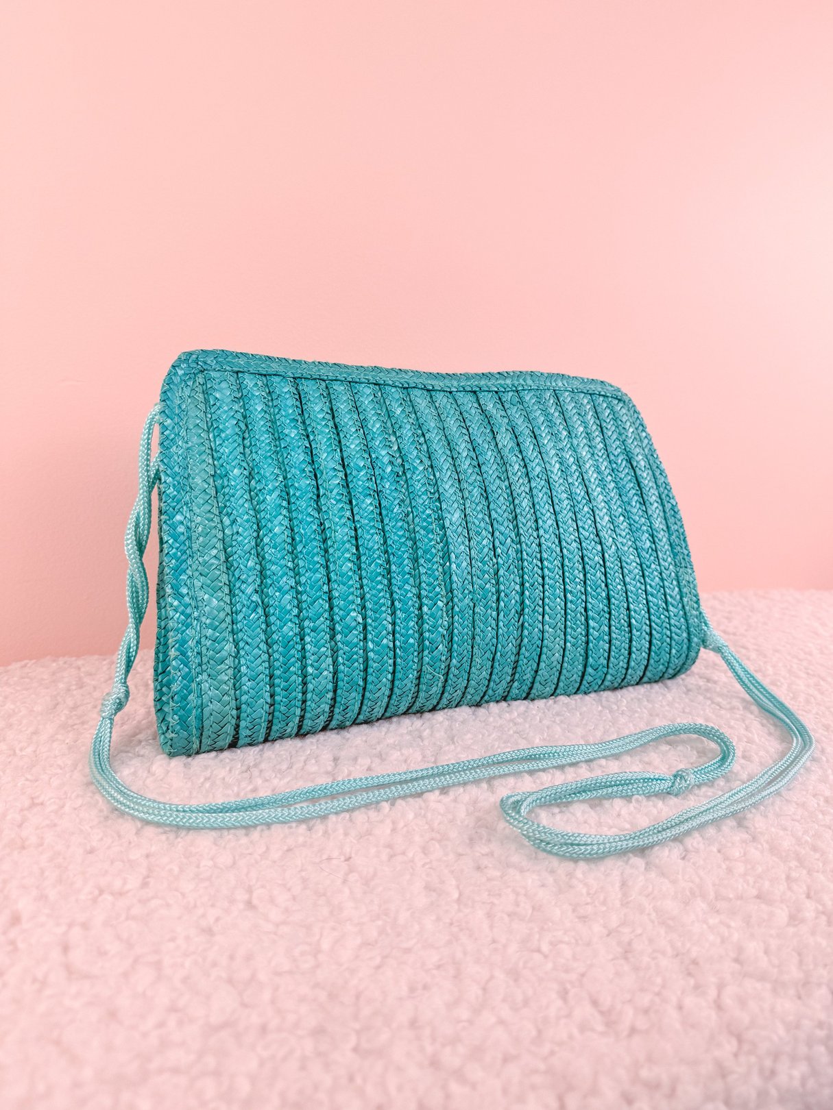 Teal blue woven shoulder bag with a single strap, featuring a curved design typical of 1970s style.