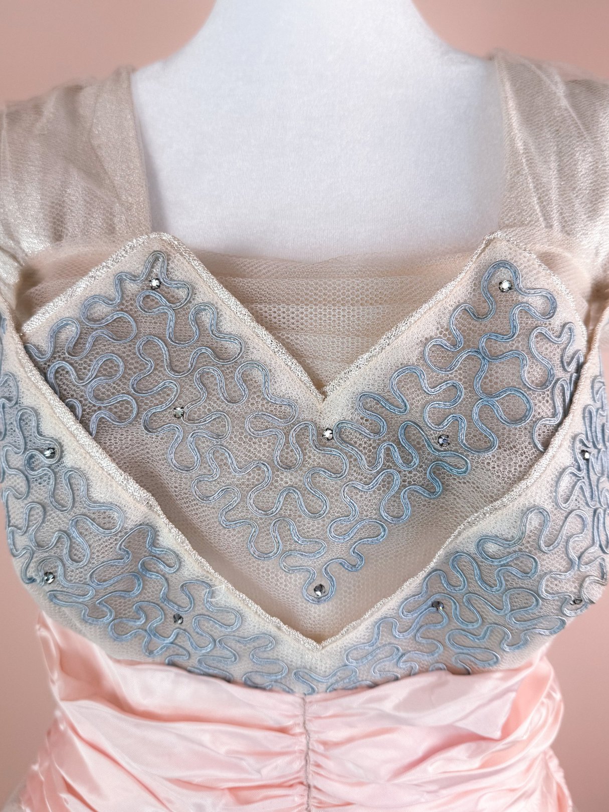 The Twilight Waltz Dress features a silver 1950s design with intricate blue embroidered detailing and sparkle accents.