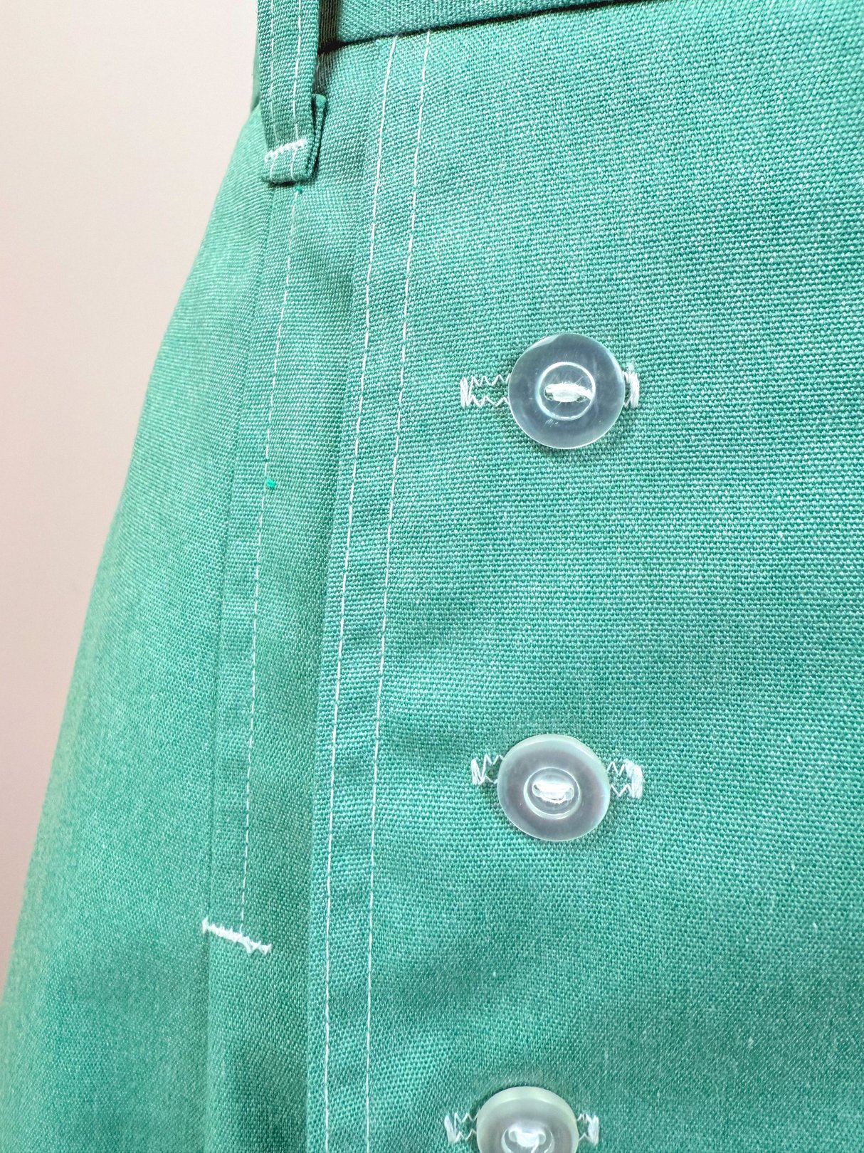 Green 1970s women's skort featuring transparent buttons and visible stitching details.
