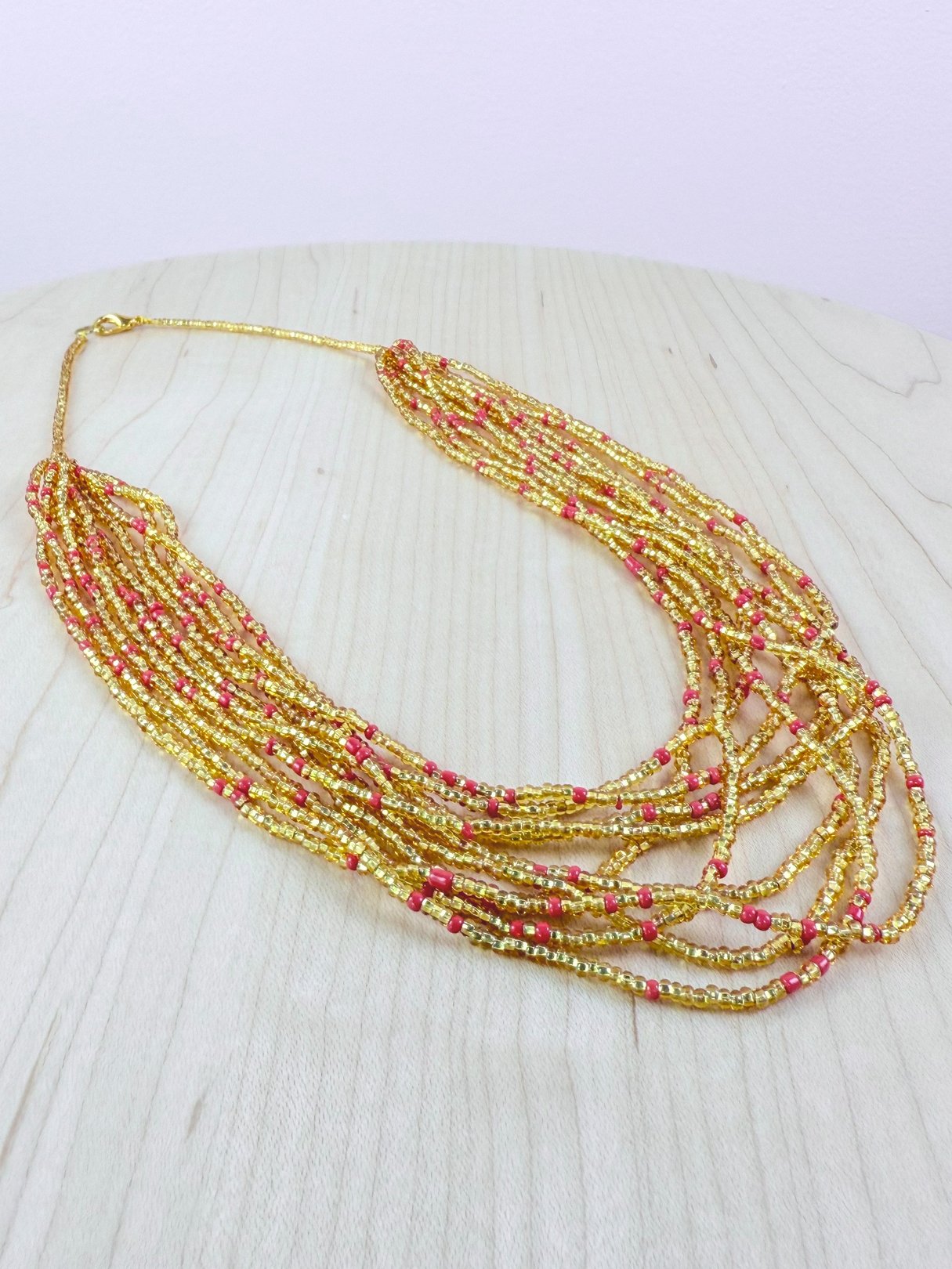 Shimmering gold marigold necklace with multiple strands and pink accents, characteristic of 1990s women's jewelry.