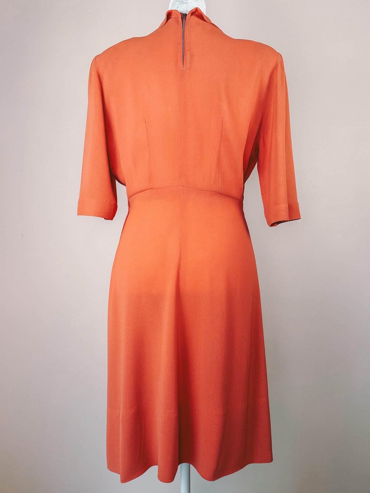 1940s coral recital dress with a structured silhouette and short sleeves, shown from the back.