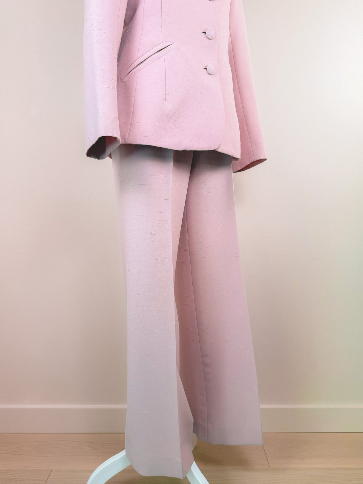 Blush pink 1970s women's three-piece suit featuring a blazer with two buttons, matching wide-leg trousers, and structured fabric.