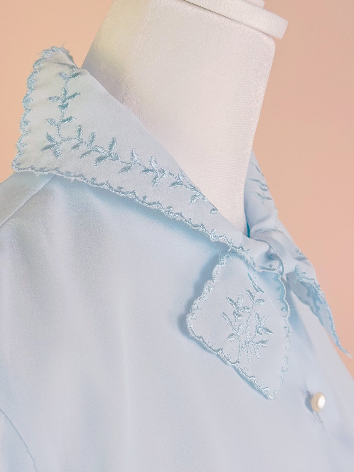 Powder blue blouse for women featuring a scalloped collar with floral embroidery, reflecting a 1950s style.