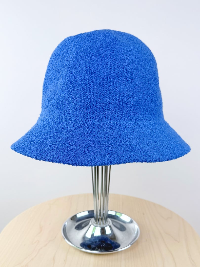 Cobalt blue bucket hat made of textured fabric, displaying a wide brim and a rounded crown, suitable for women and inspired by 1960s fashion.