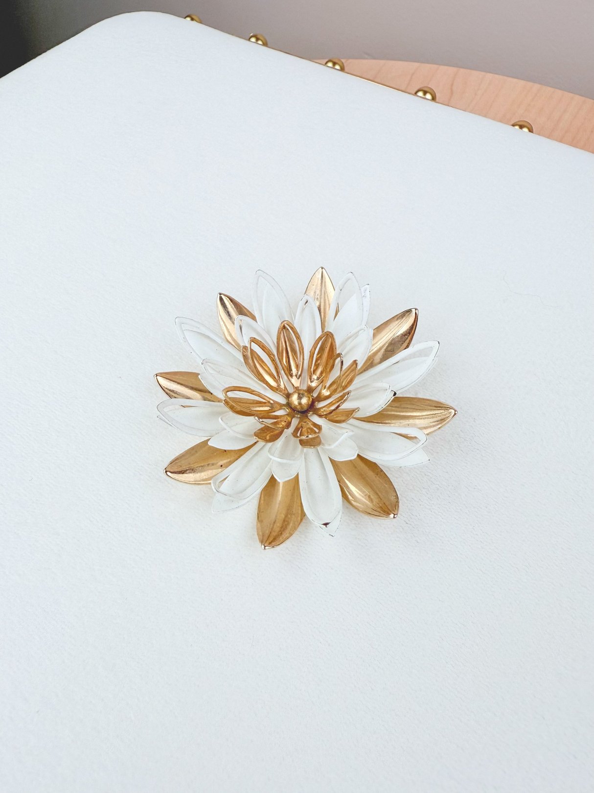 A gold and white Gilded Dahlia brooch from the 1950s, designed for women, featuring a layered flower petal design.