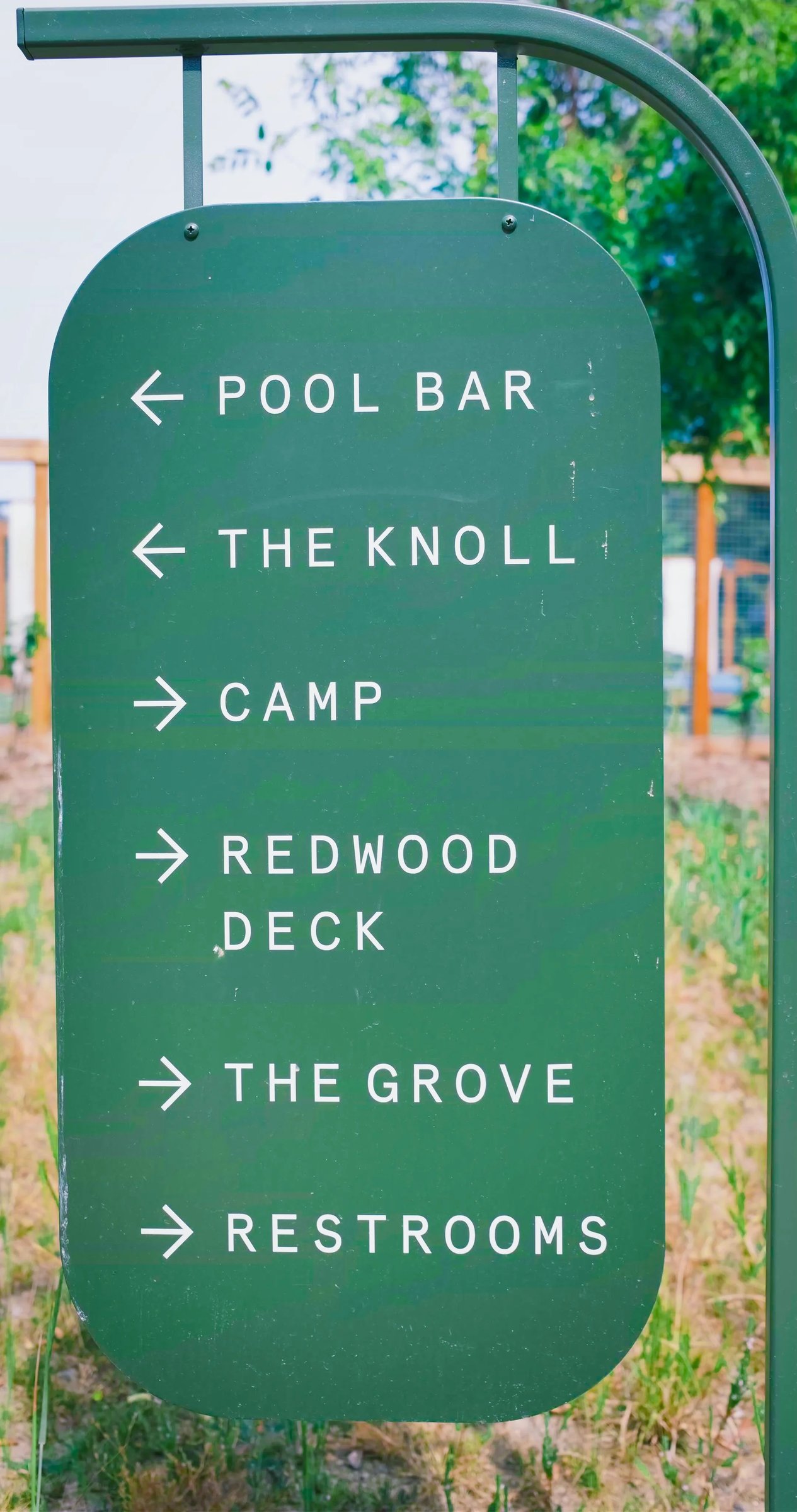 A directional sign indicating the locations of the Pool Bar, The Knoll, Camp, Redwood Deck, The Grove, and Restrooms.