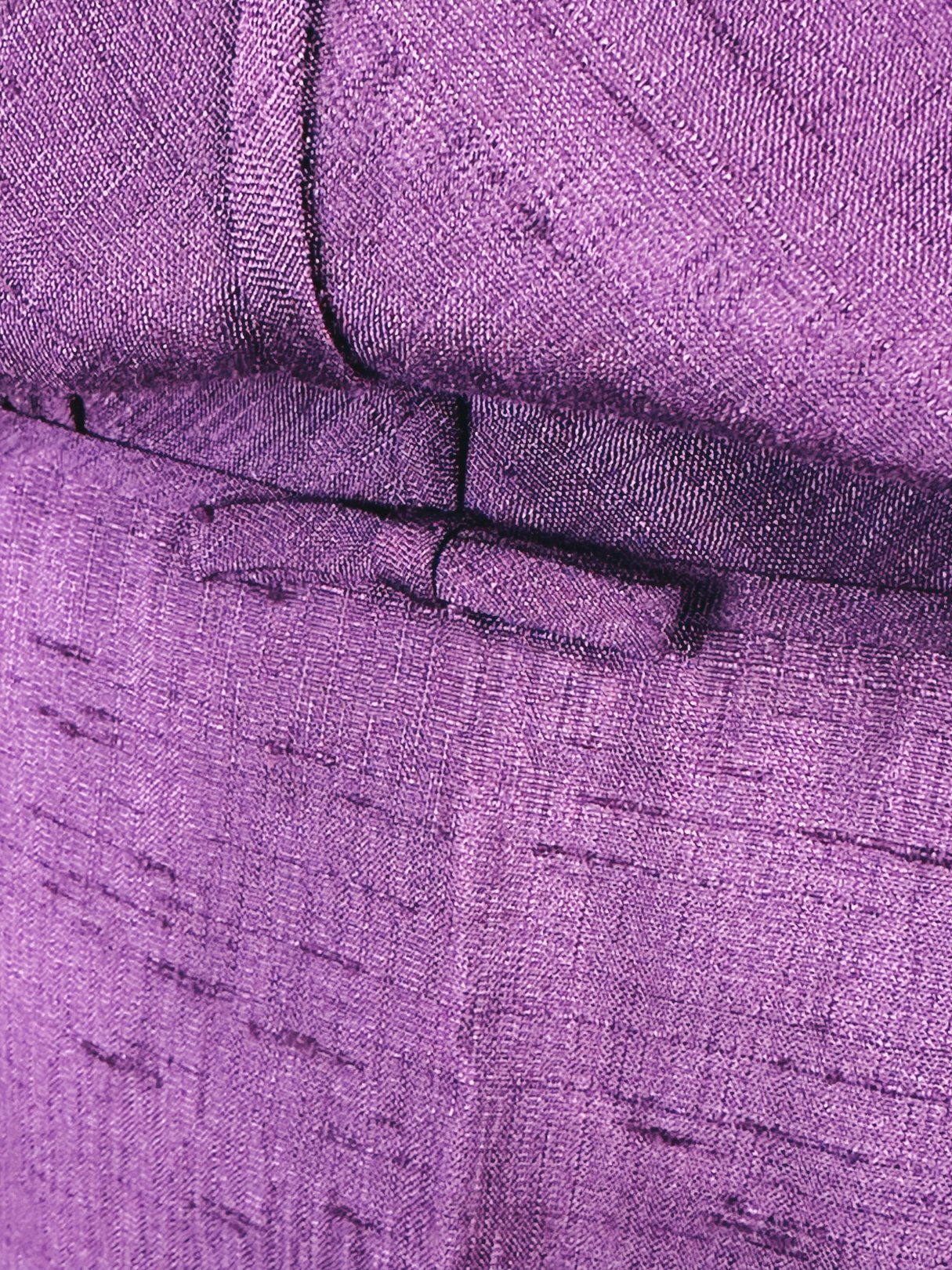 Close-up detail of a purple dress featuring a bow, indicative of 1960s fashion.