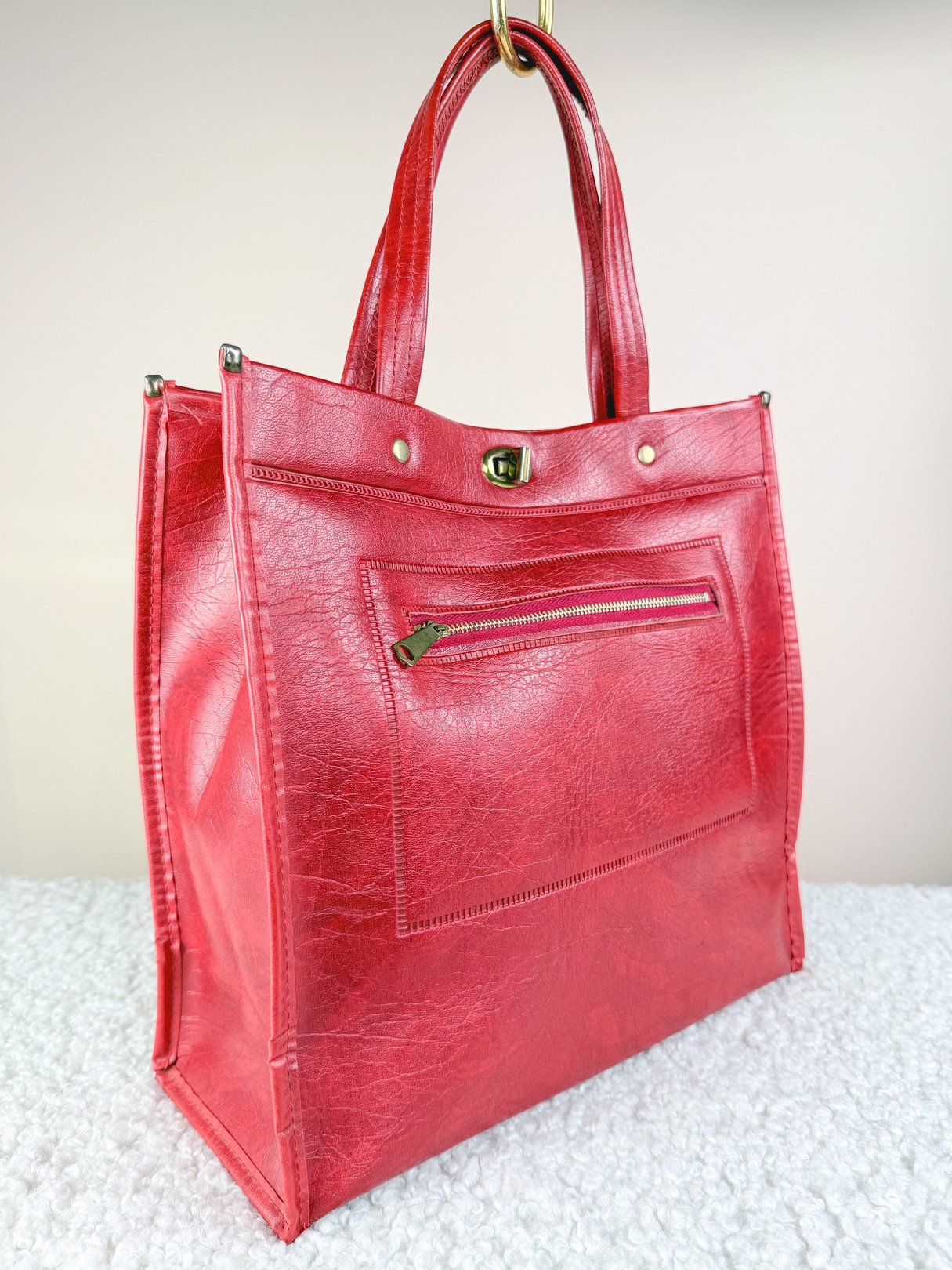 A 1970s women's red tote bag with a front zip pocket and two handles.