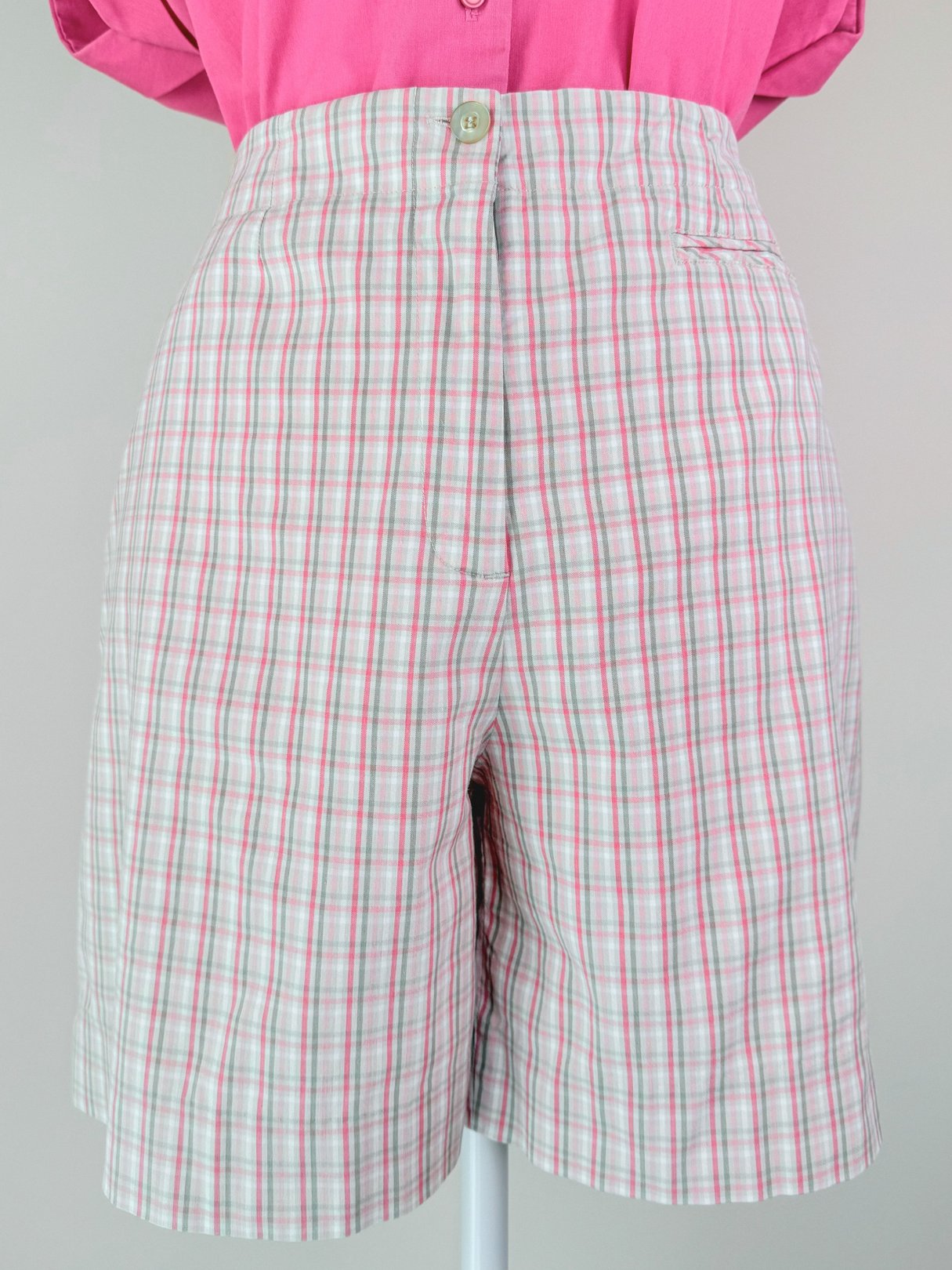 Women’s 1980s pink plaid shorts featuring a button closure and front pocket.