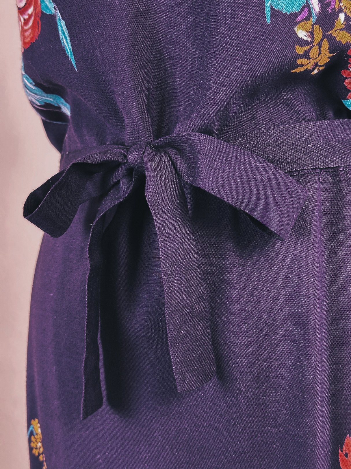Purple dress featuring a tie waist and floral embroidery, representative of 1970s women's fashion.