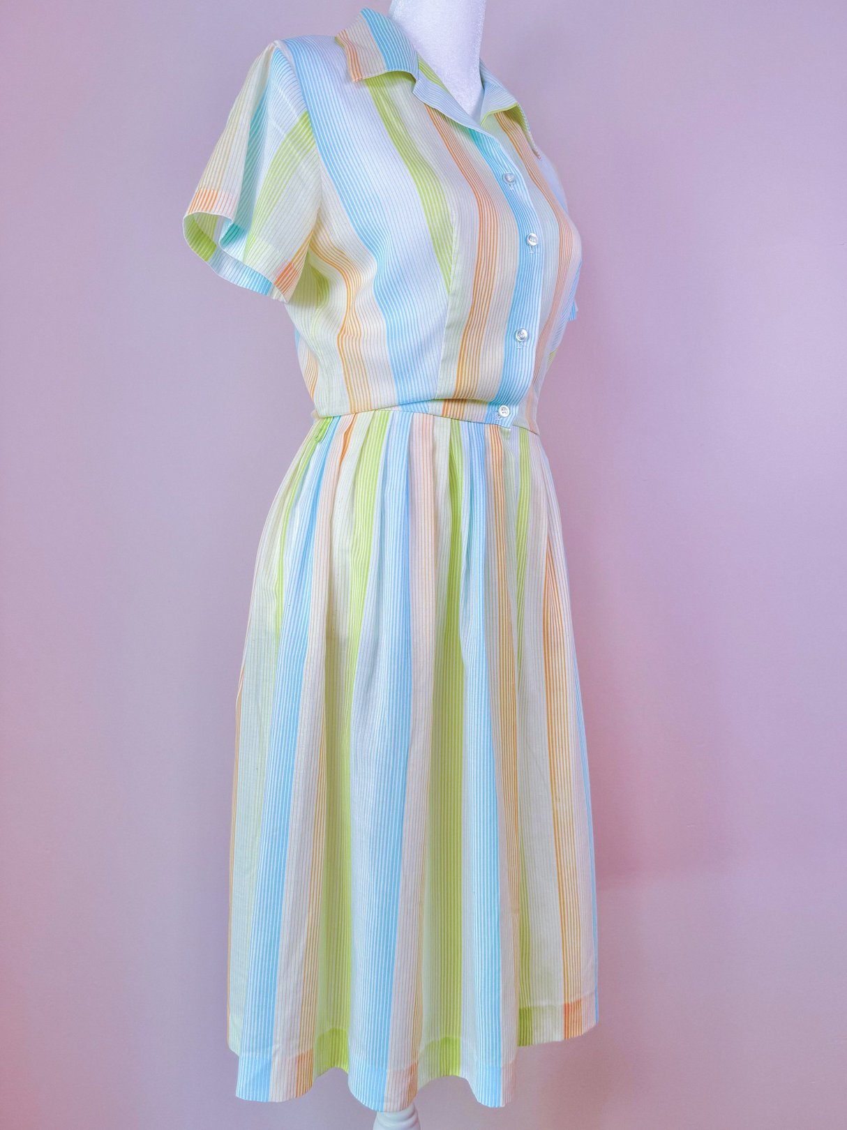 1950s women's Citrus Dress featuring a colorful striped pattern in orange, blue, and green with short sleeves and a button-down front.