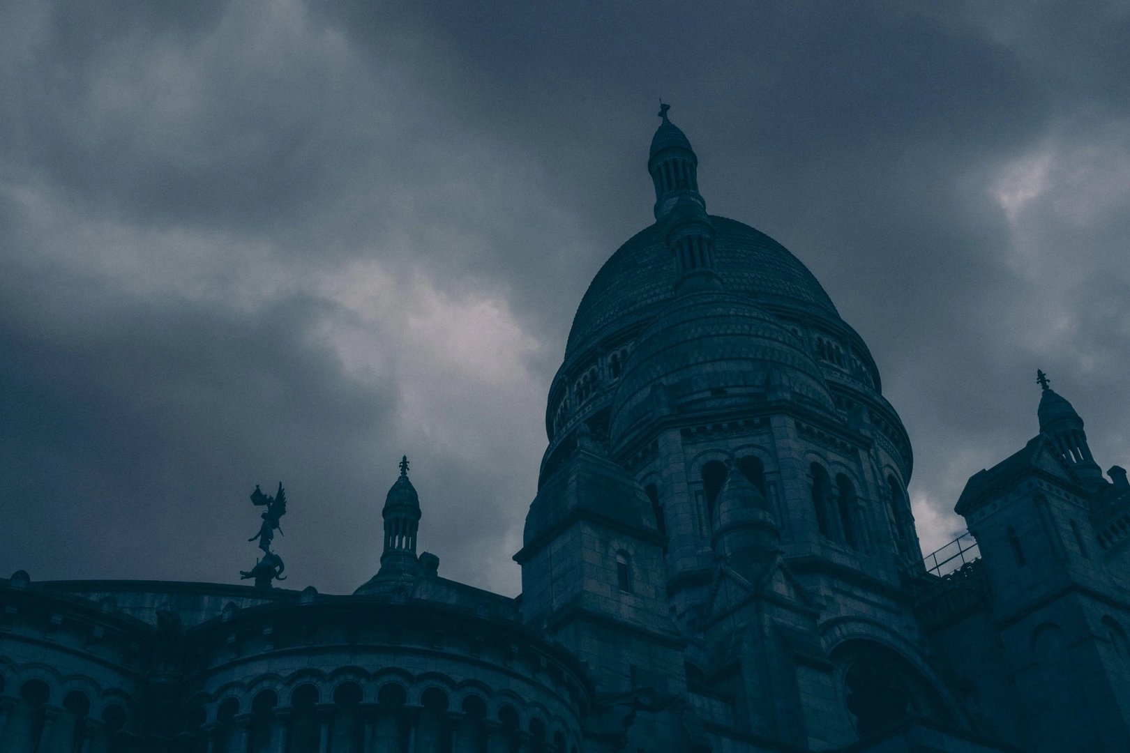 The dome of a historic building towers against a dark, cloudy sky.