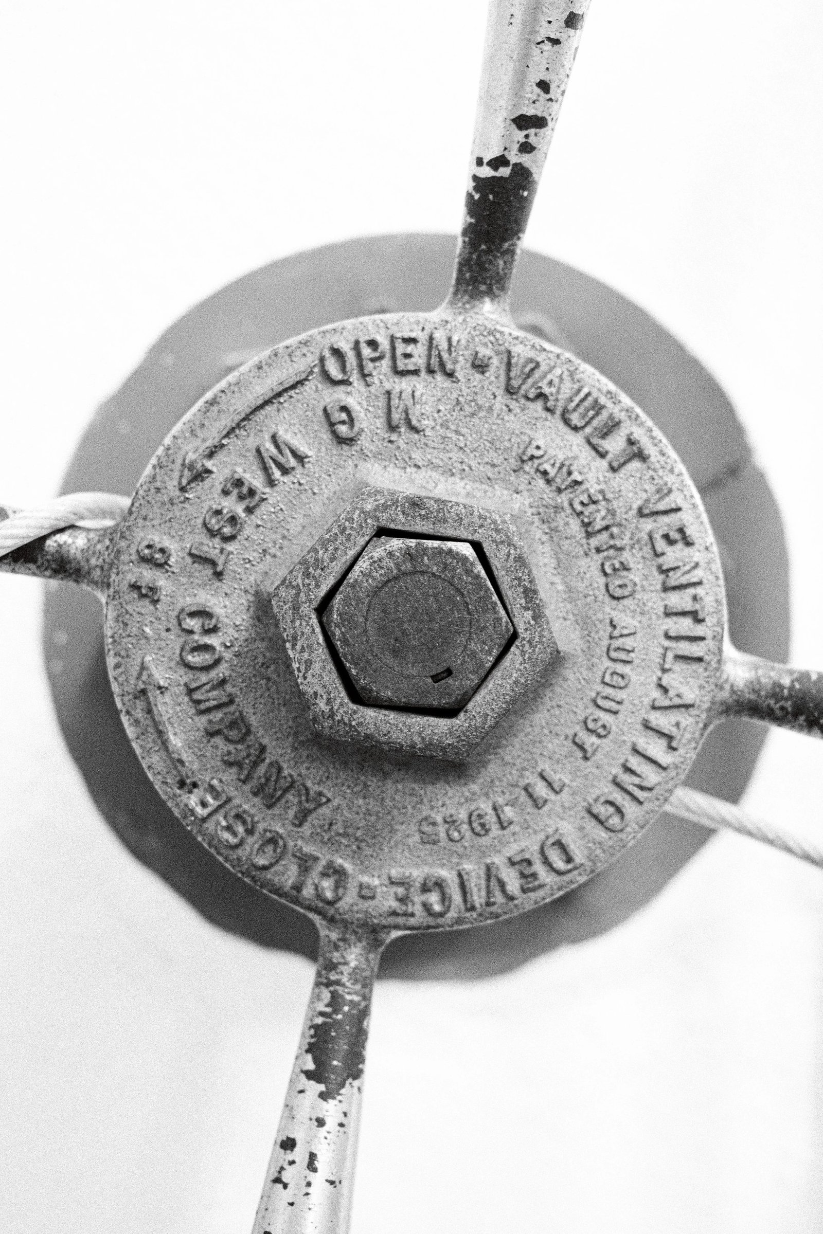 Close-up of a vintage vault lock mechanism with engraved details and a rusty finish.