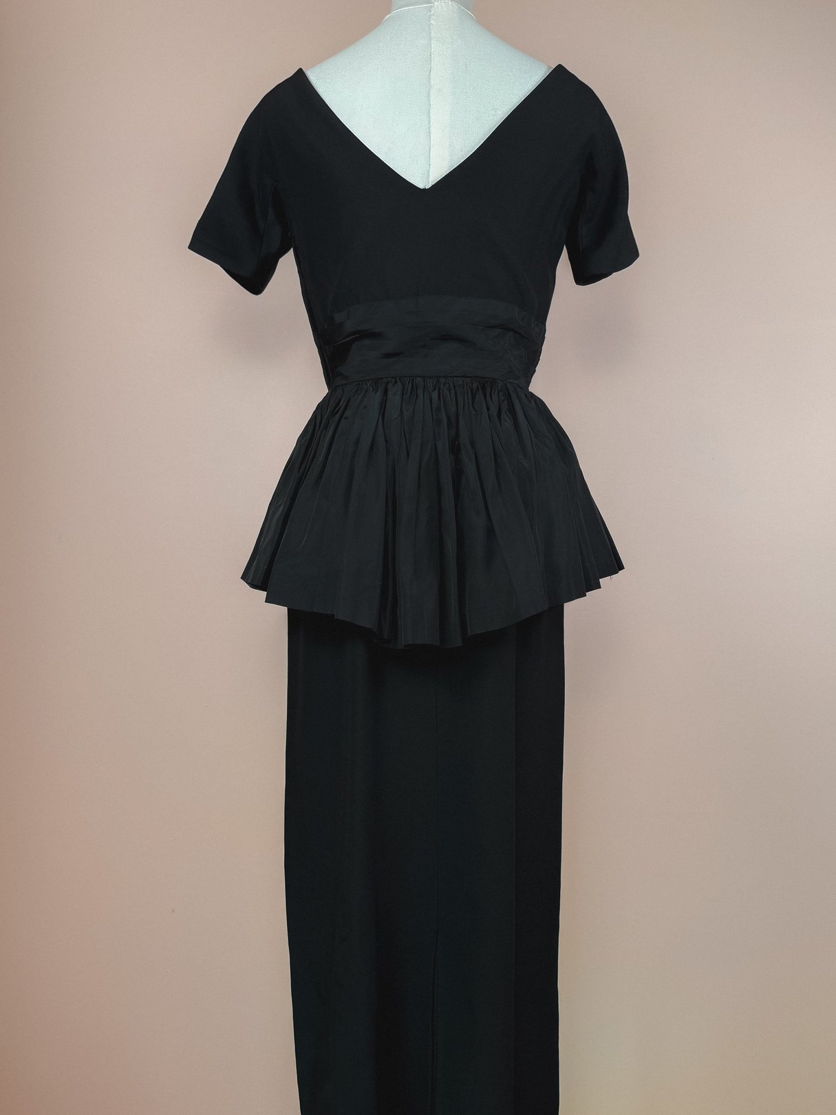 Black 1950s women's dress featuring a fitted bodice and a flared, pleated skirt.
