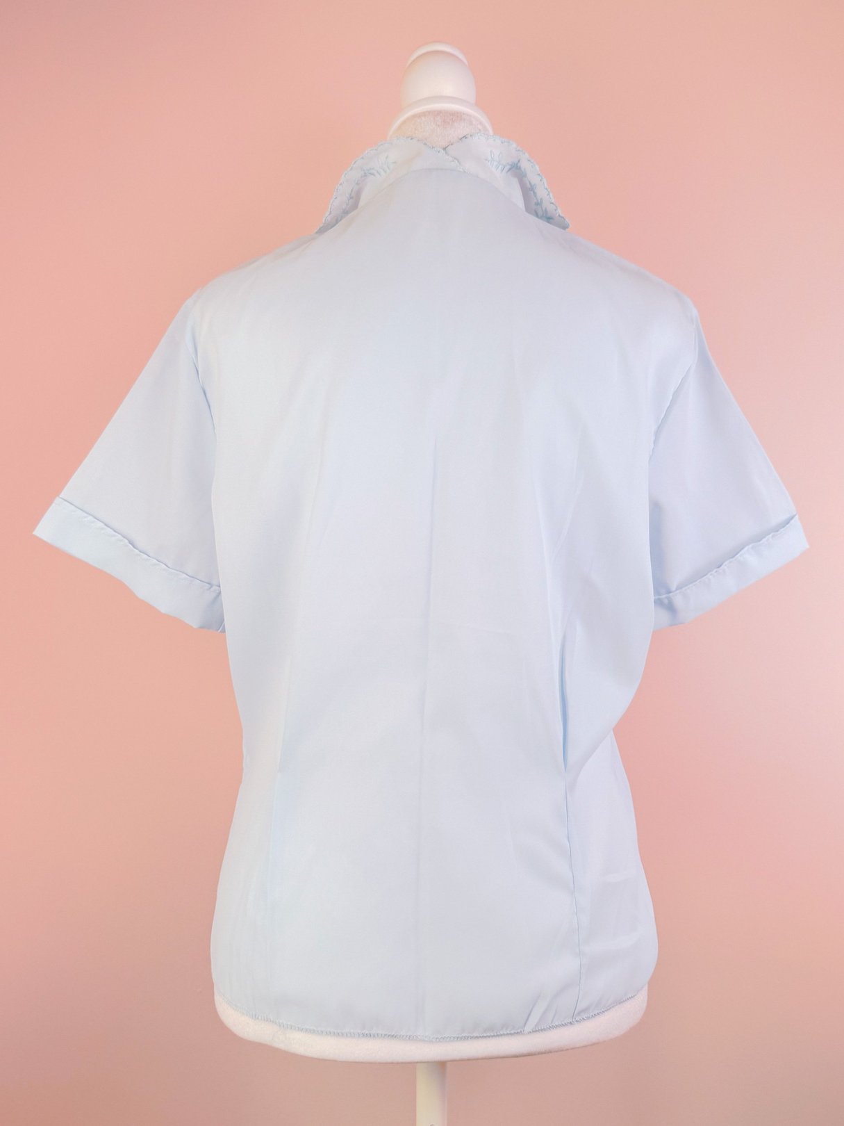 Powder blue blouse for women featuring a short-sleeve design and lace detail at the collar, styled from the 1950s.