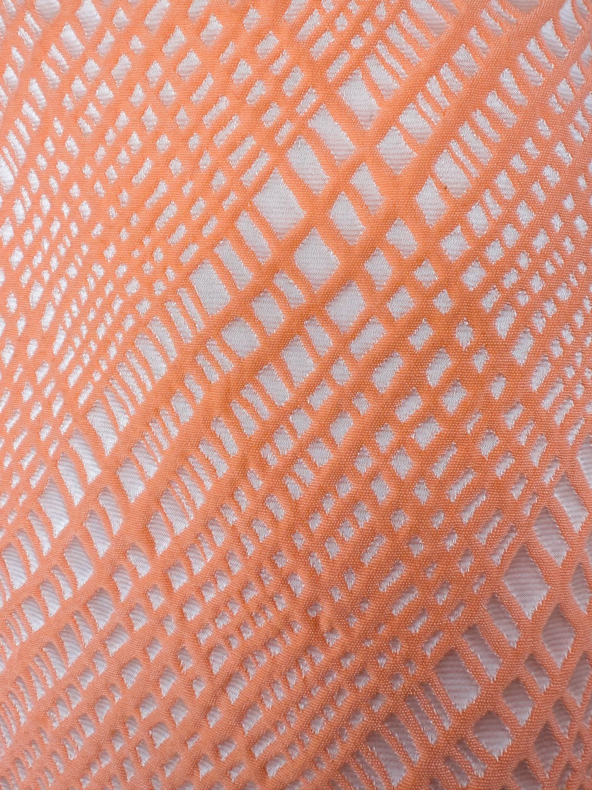 Close-up of an orange textile featuring a textured grid pattern, suitable for a 1960s women’s dress.