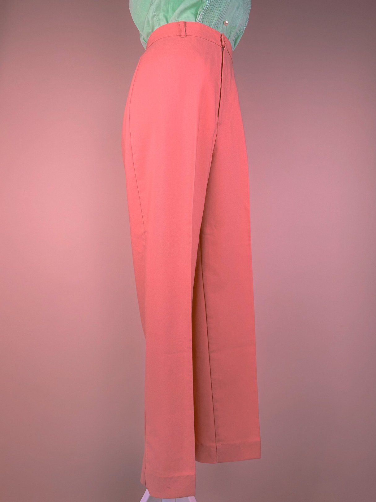 Coral pink wide-leg pants with a high waist, styled in a 1970s fashion.