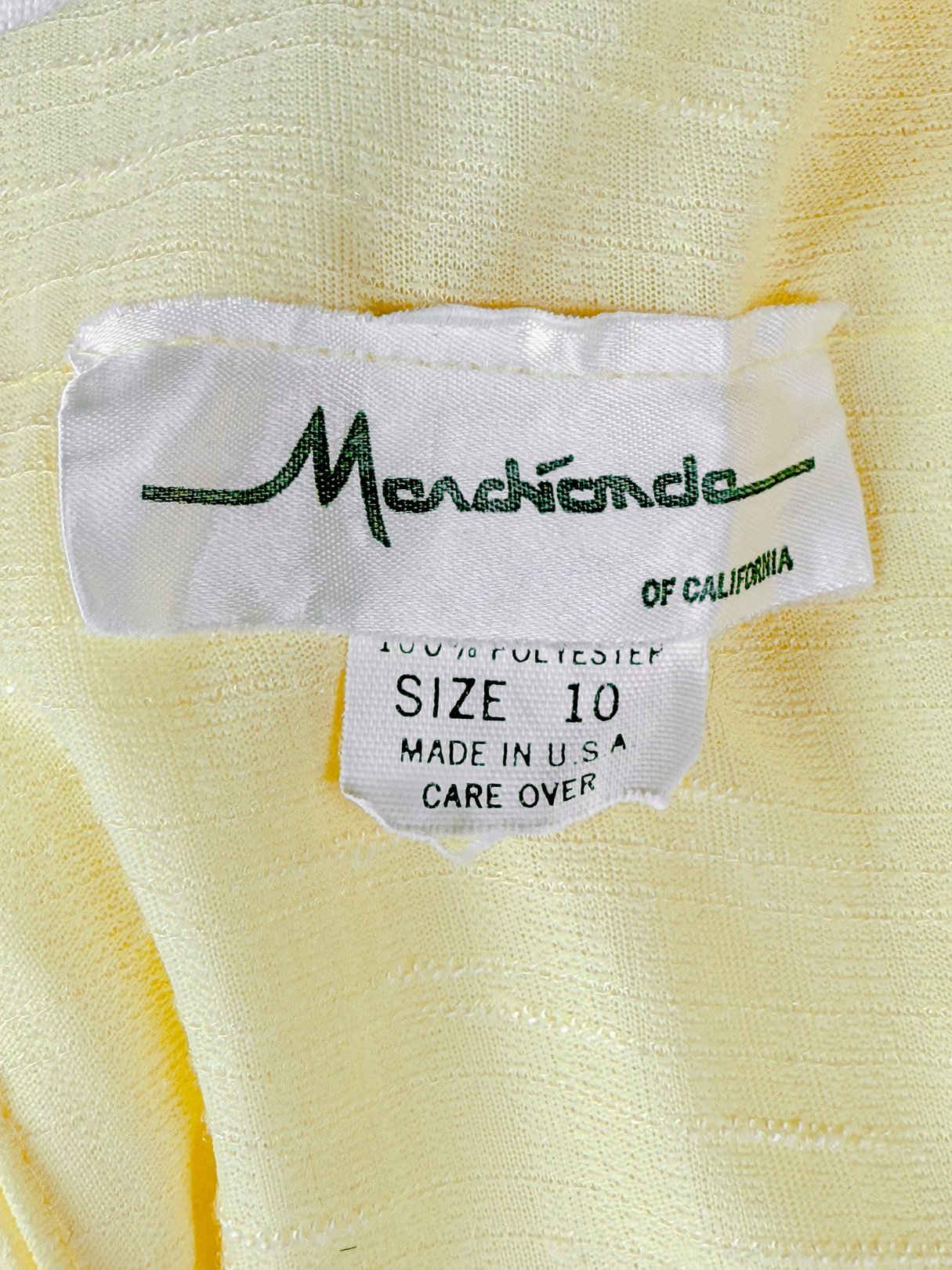 Label tag displaying "Mondhiene of California," indicating the dress is a size 10, made of 100% polyester, and in lemon yellow color.