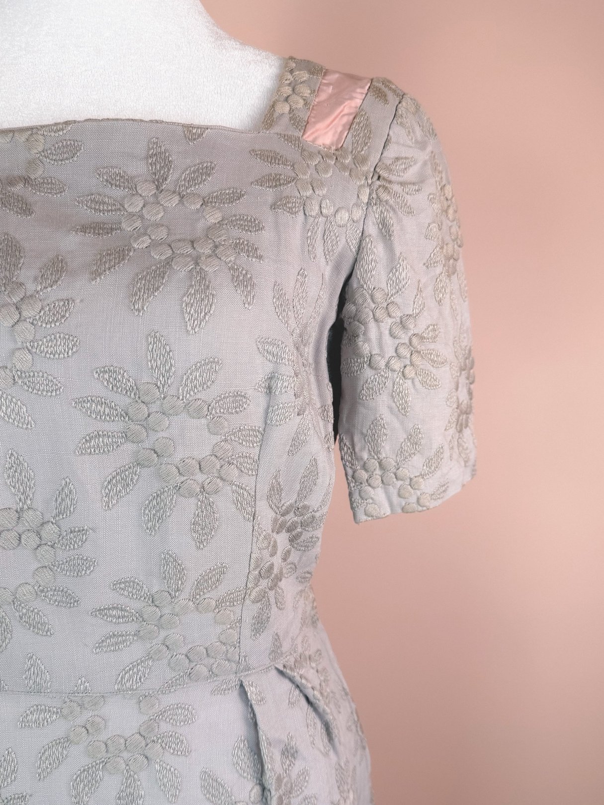 Slate blue 1950s women's dress with a textured floral pattern and satin accents on the shoulder.