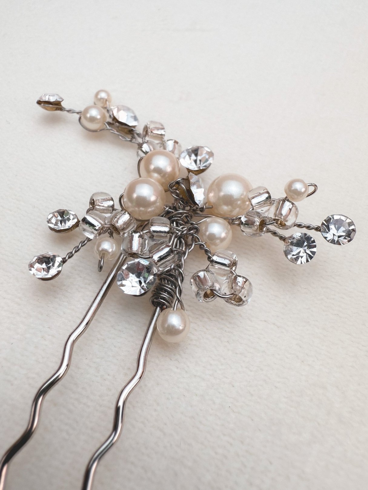 A vintage 1970s women's hair pin featuring silver-toned wires adorned with pearls and sparkling rhinestones.