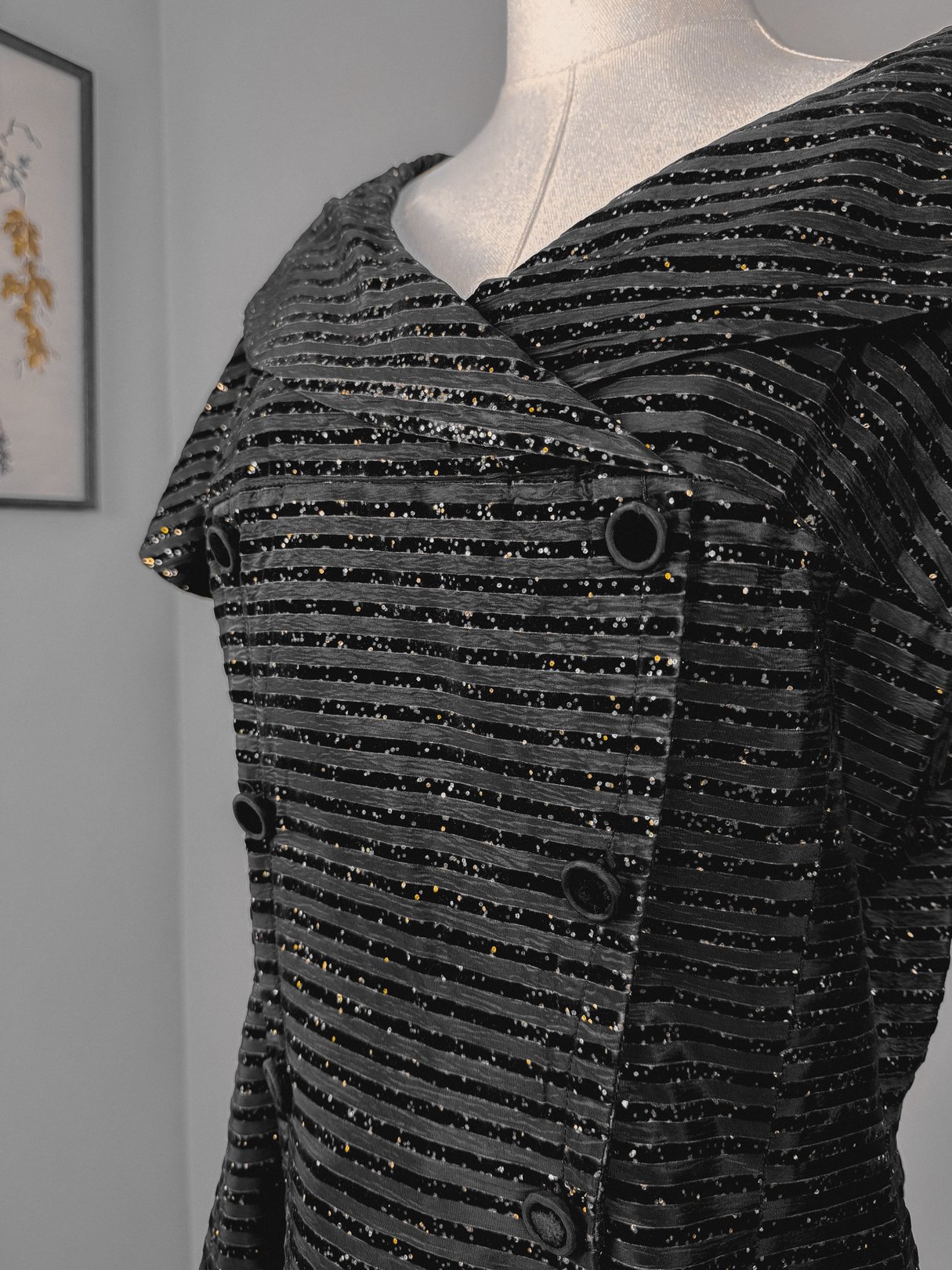 A 1950s black confetti party dress featuring a textured fabric with vertical stripes and a wide collar, displayed on a mannequin.