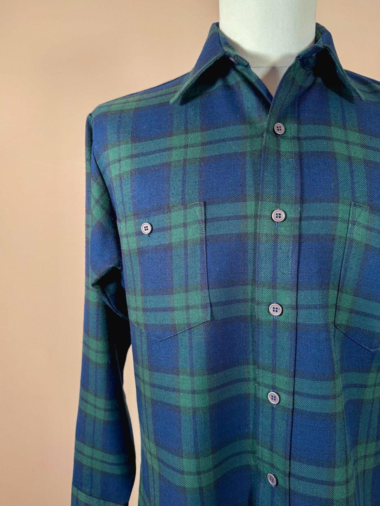 Navy blue 1950s men's plaid shirt featuring green accents and two front pockets.